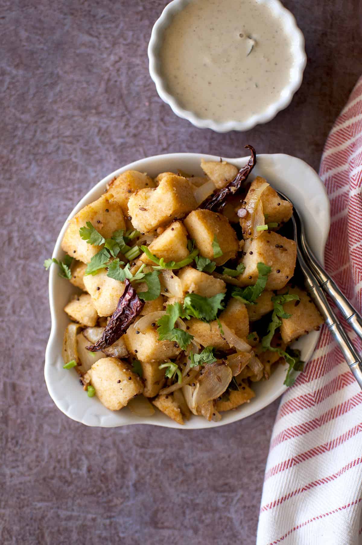 White plate with Masala Idli and chutney in a small bowl