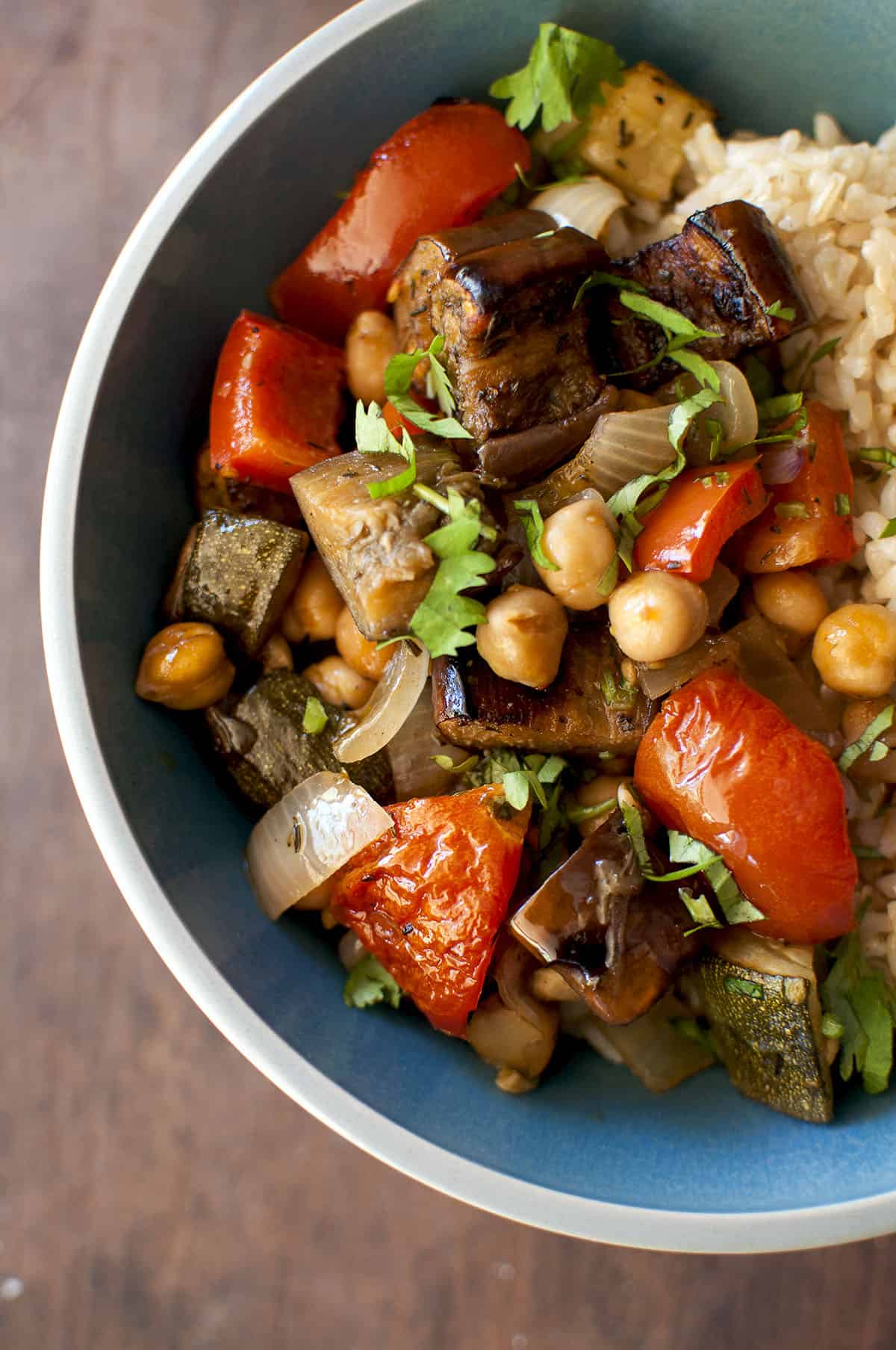 Grey bowl with roasted ratatouille garnished with fresh herbs