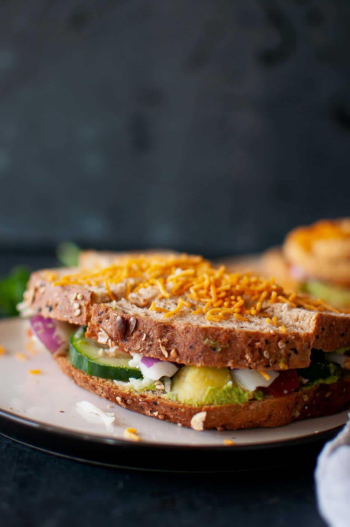 White plate with green chutney sandwich topped with sev.