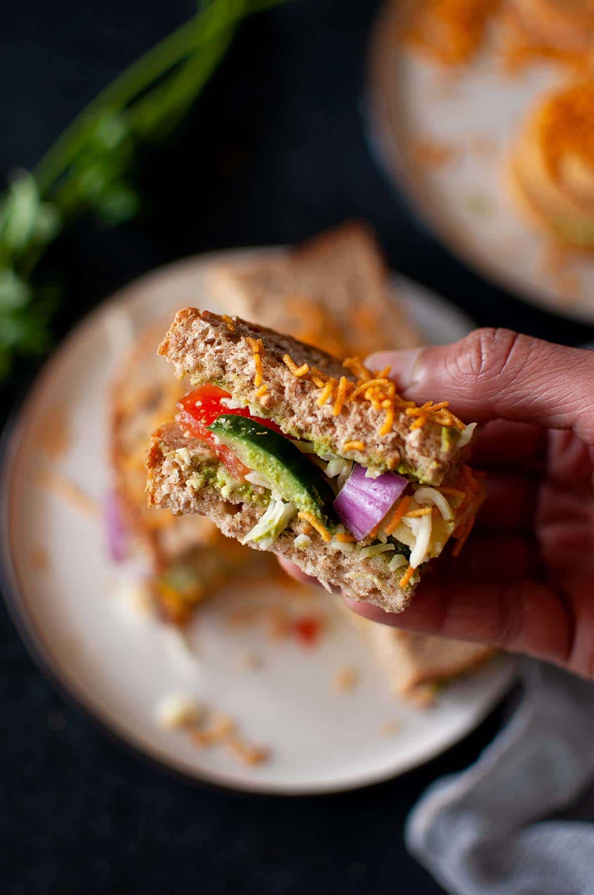 Hand holding quarter of a green chutney sandwich.