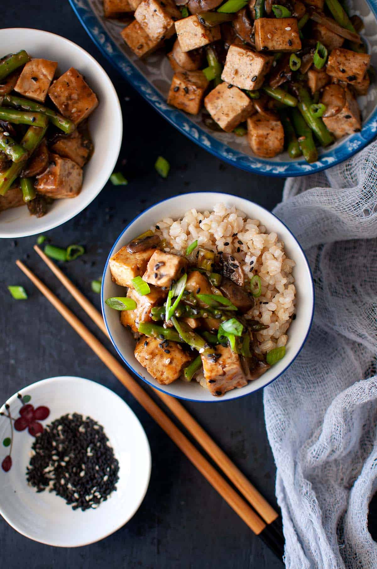 White bowl with tofu asparagus stir fry and brown rice.