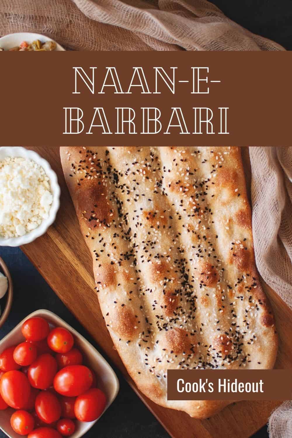 Wooden board with Naan e barbari bread with bowls of tomato, cheese on the side.