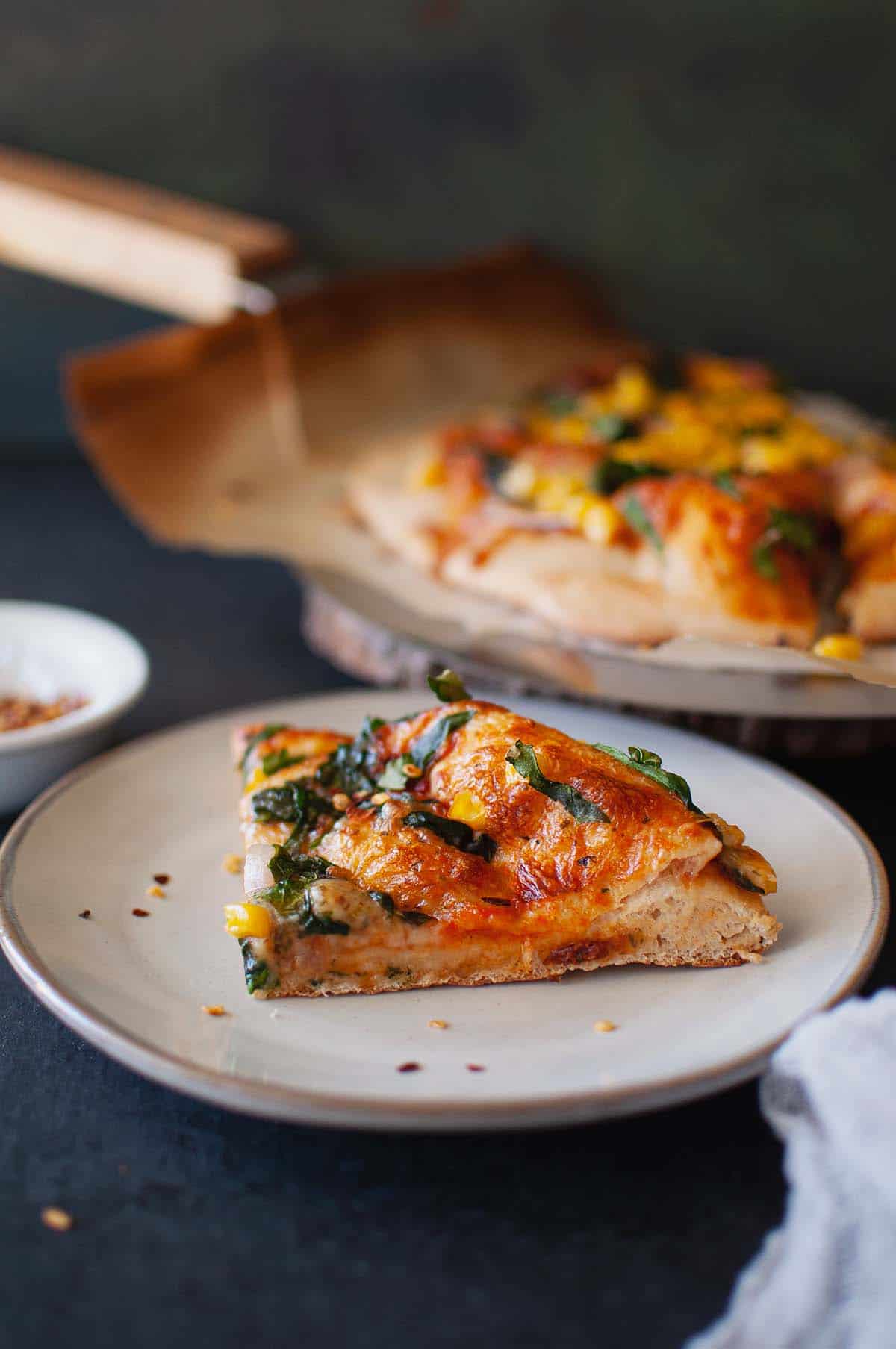 Grey plate with a slice of veggie pizza.