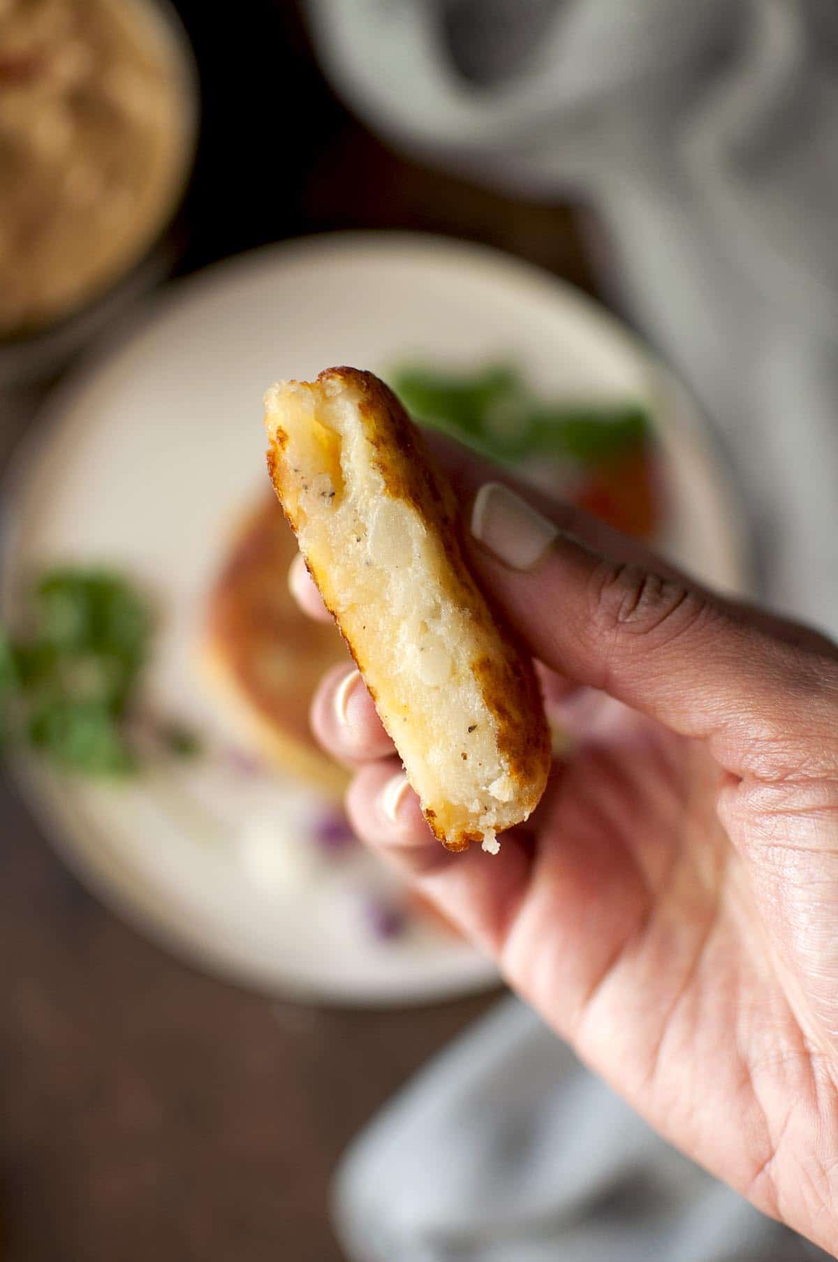 Hand holding halved potato cheese patty