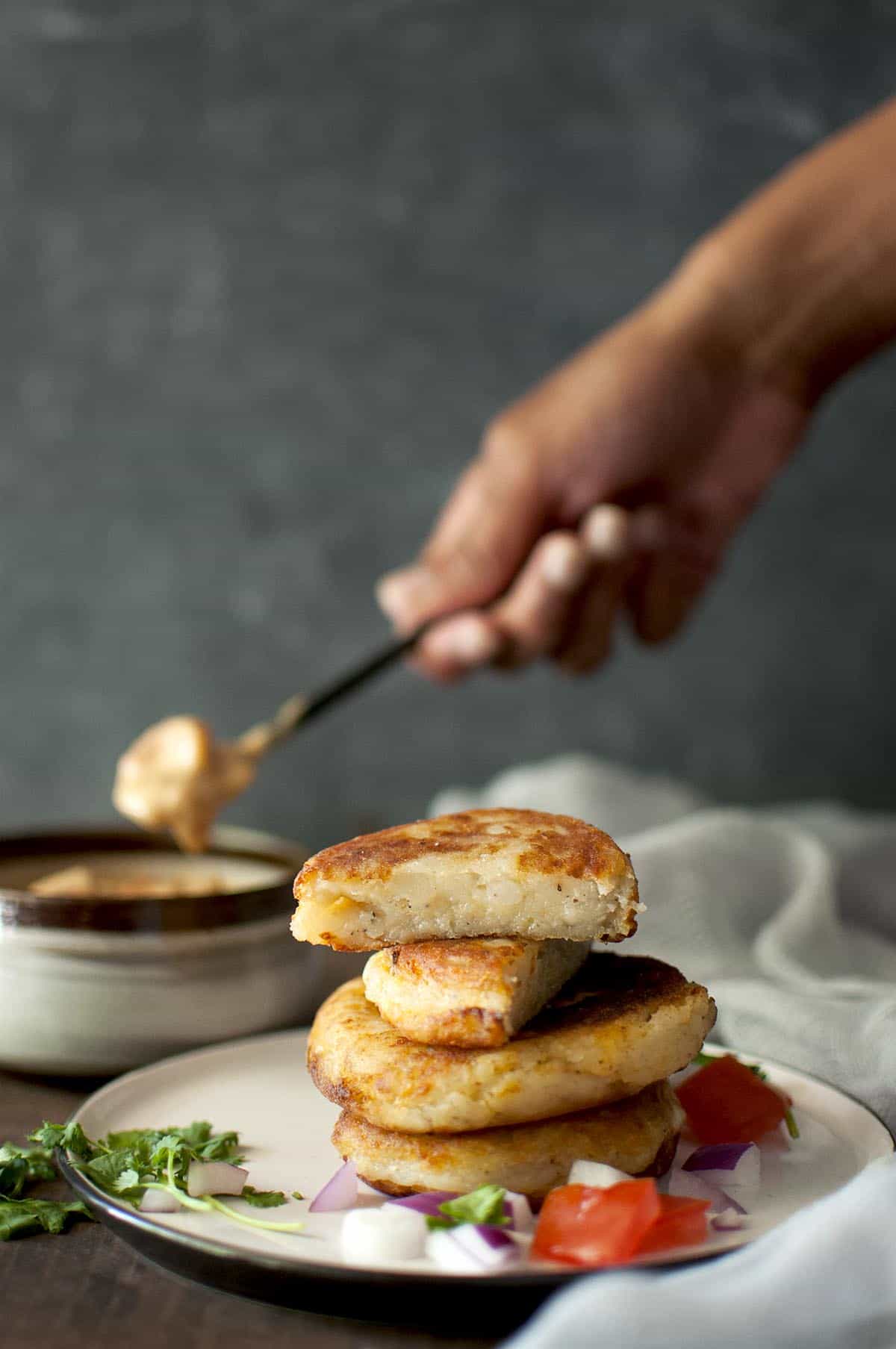 White plate with a stack of potato cheese patties