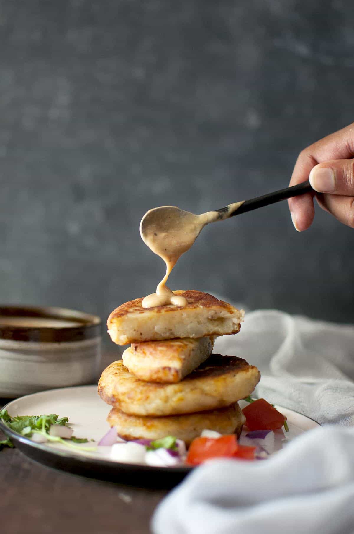 Hand drizzling peanut sauce over Llapingacho