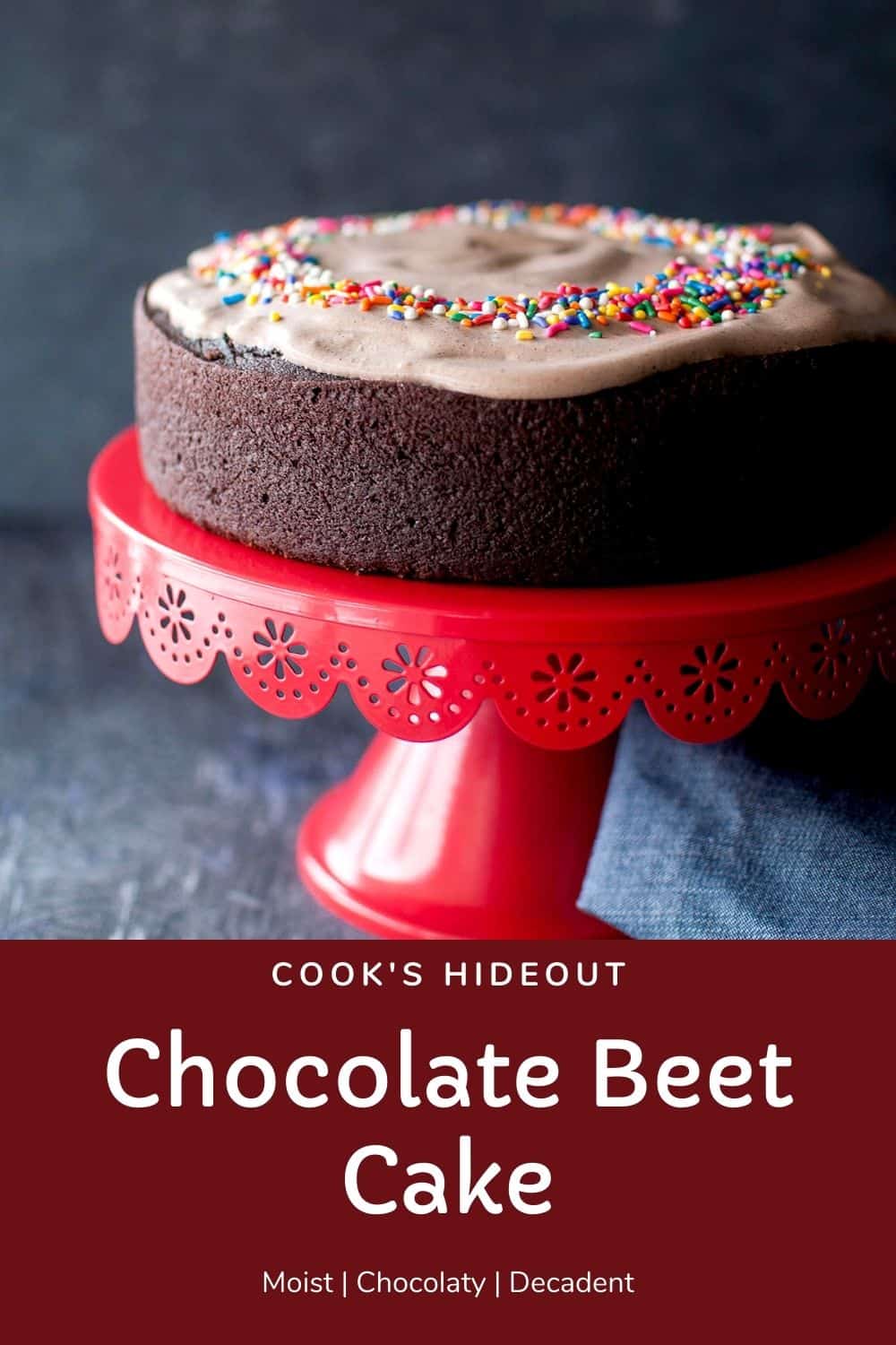 Red cake stand with the vegan chocolate beet cake topped with chocolate frosting and sprinkles