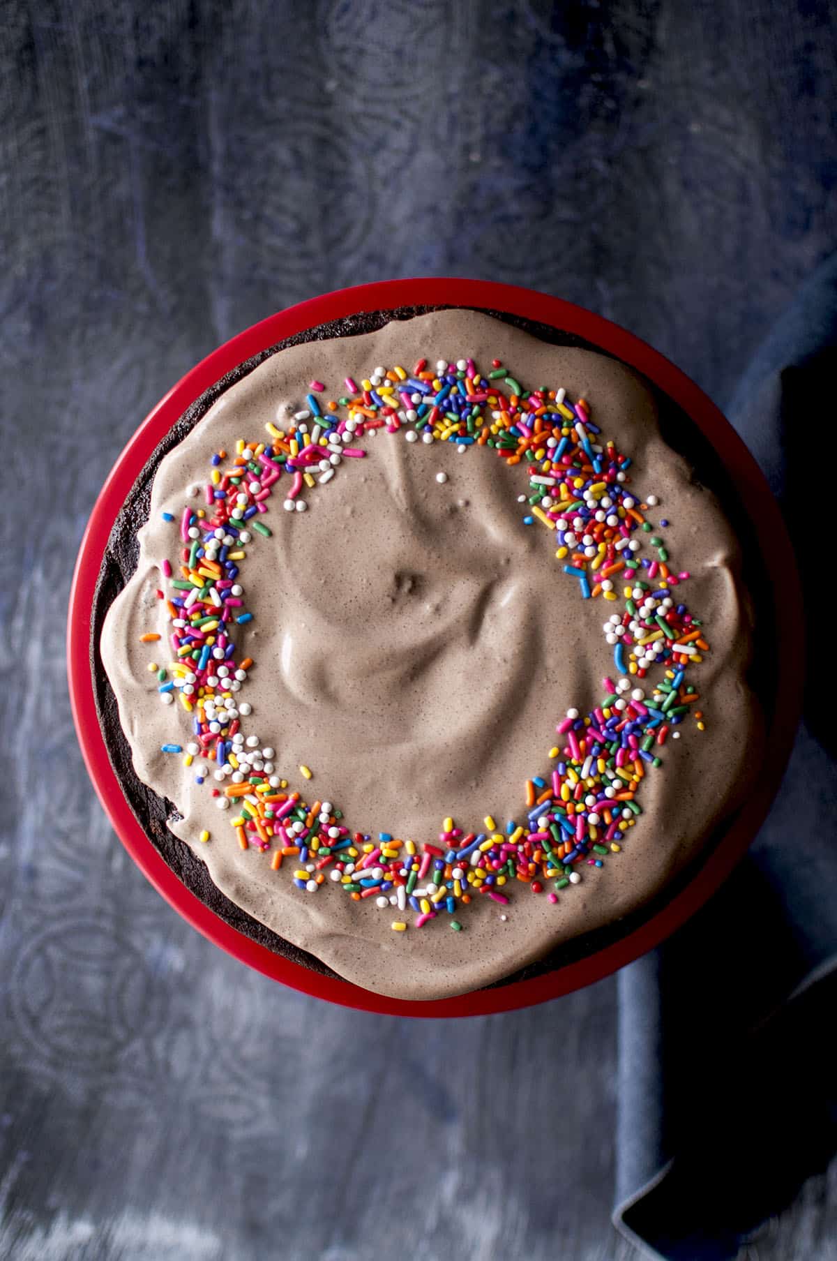 Red cake stand with chocolate beet cake topped with frosting and sprinkles