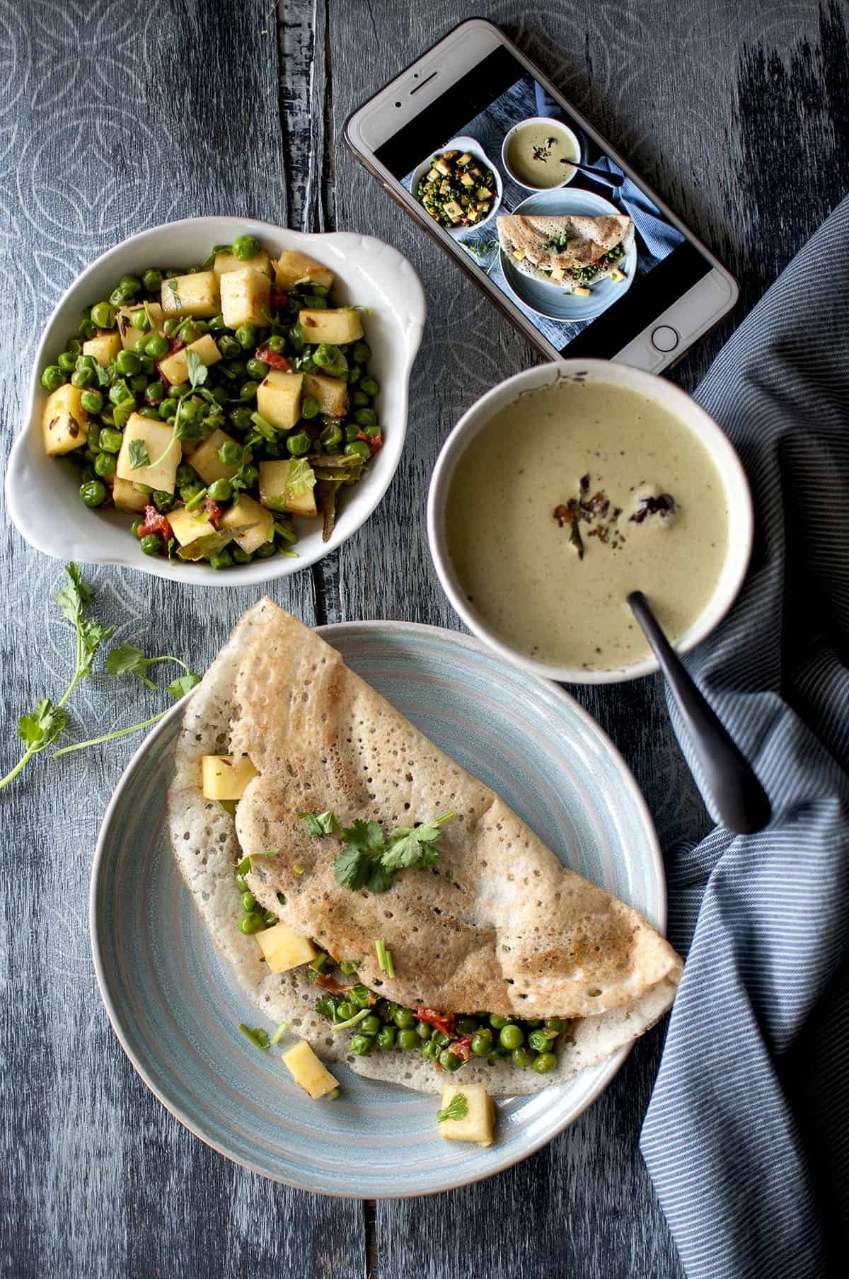 Blue plate with folded Indian crepe with paneer cubes and green peas