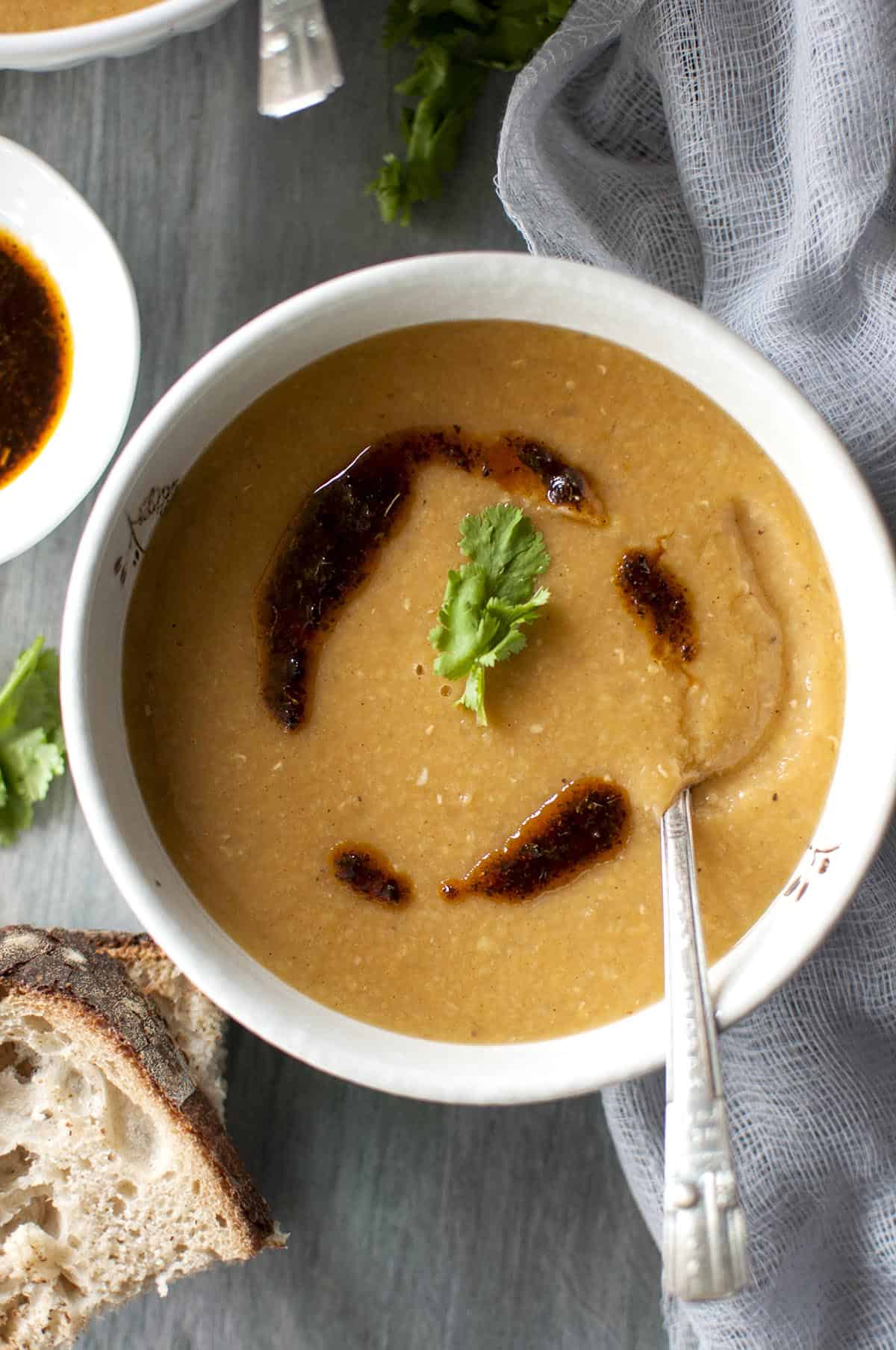 White bowl with red lentil soup drizzled with spiced melted butter