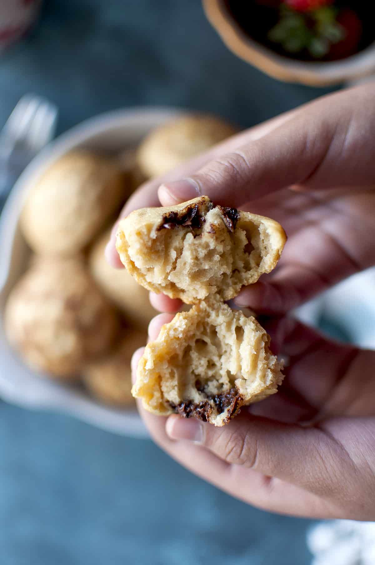 Hand holding a halved Danish pancake showing the fluffy, chocolaty inside.