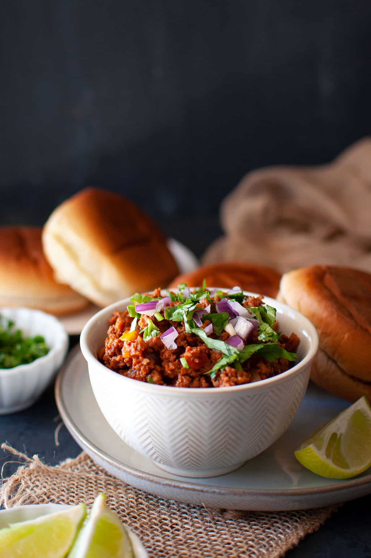 White bowl with kheema and toasted buns in the back.