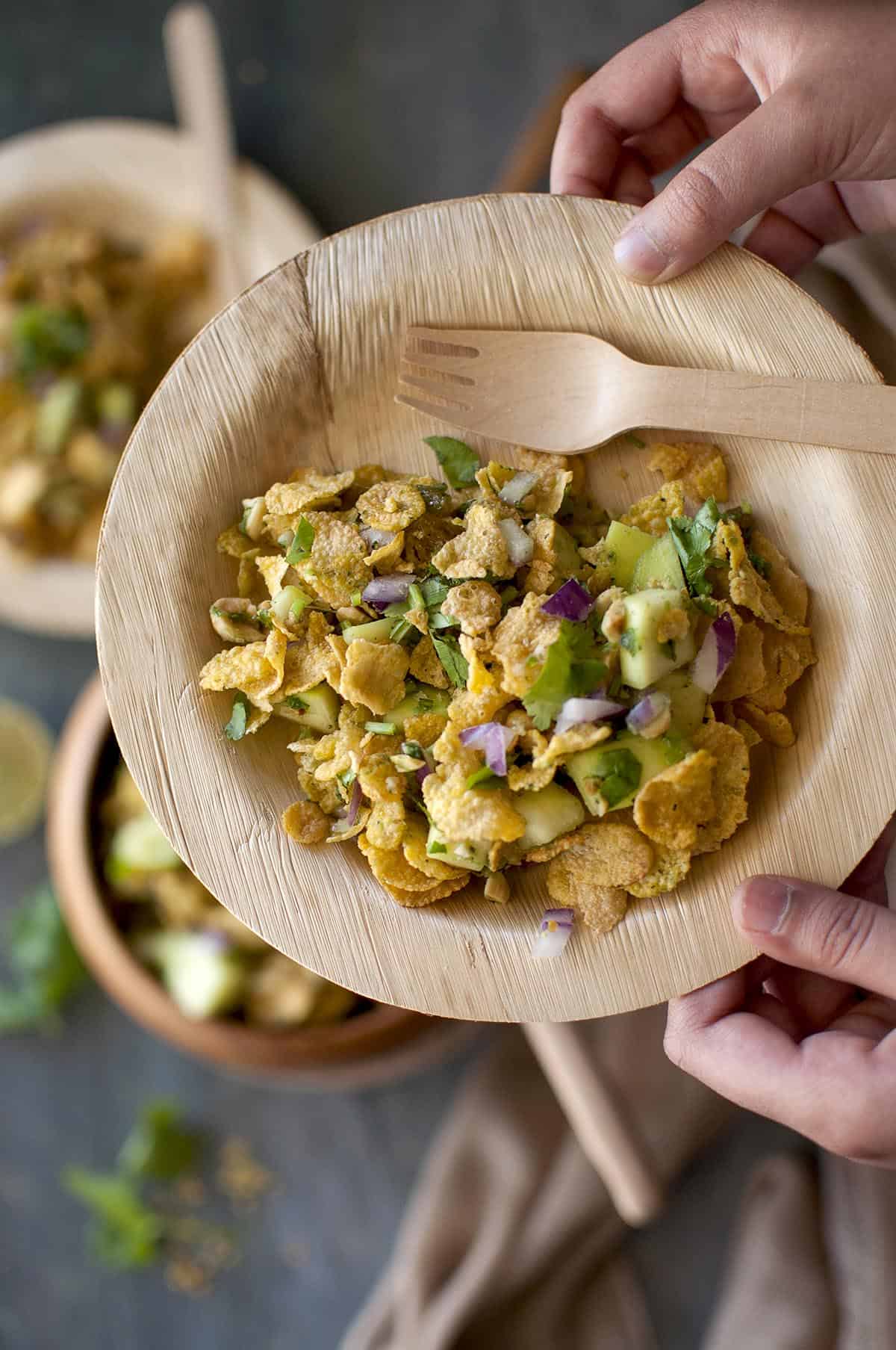 Hand holding a bamboo plate with mango salad