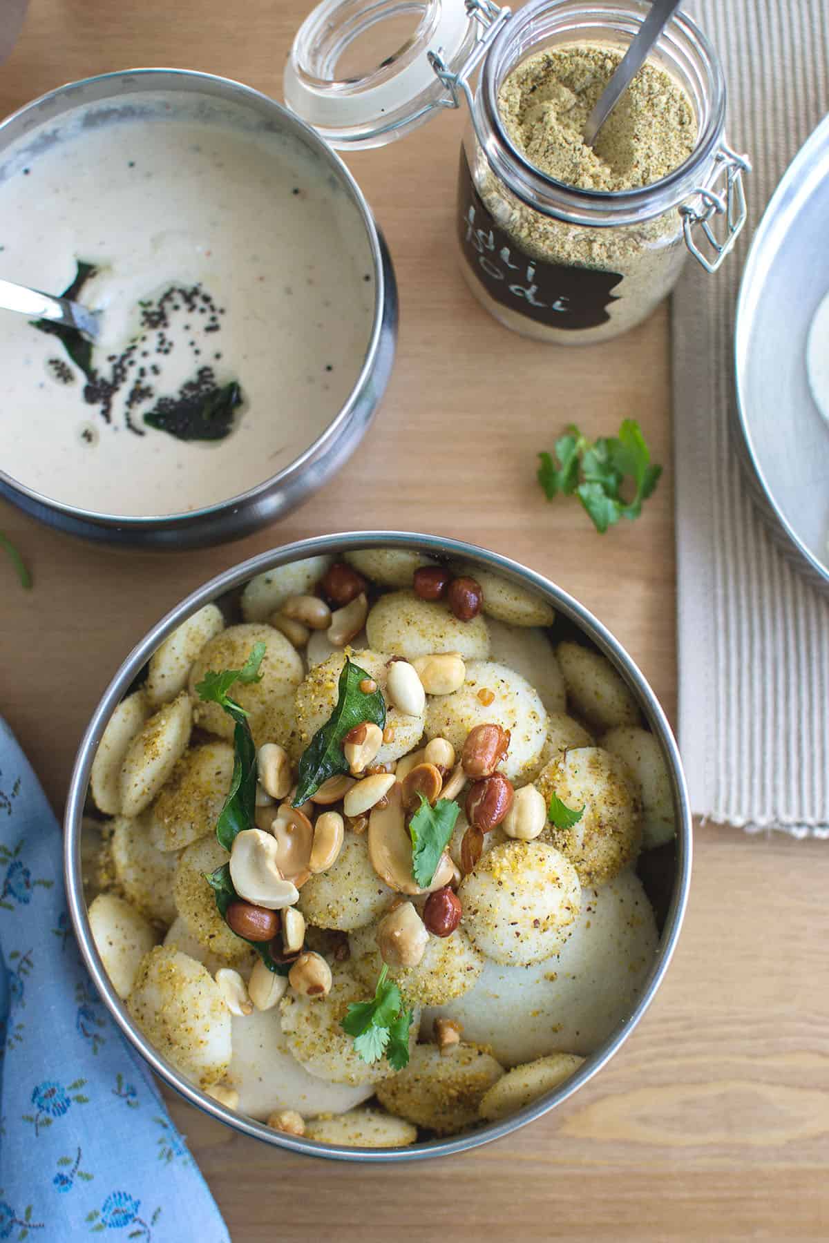 Top view of a steel bowl with idly drizzled with karam podi.