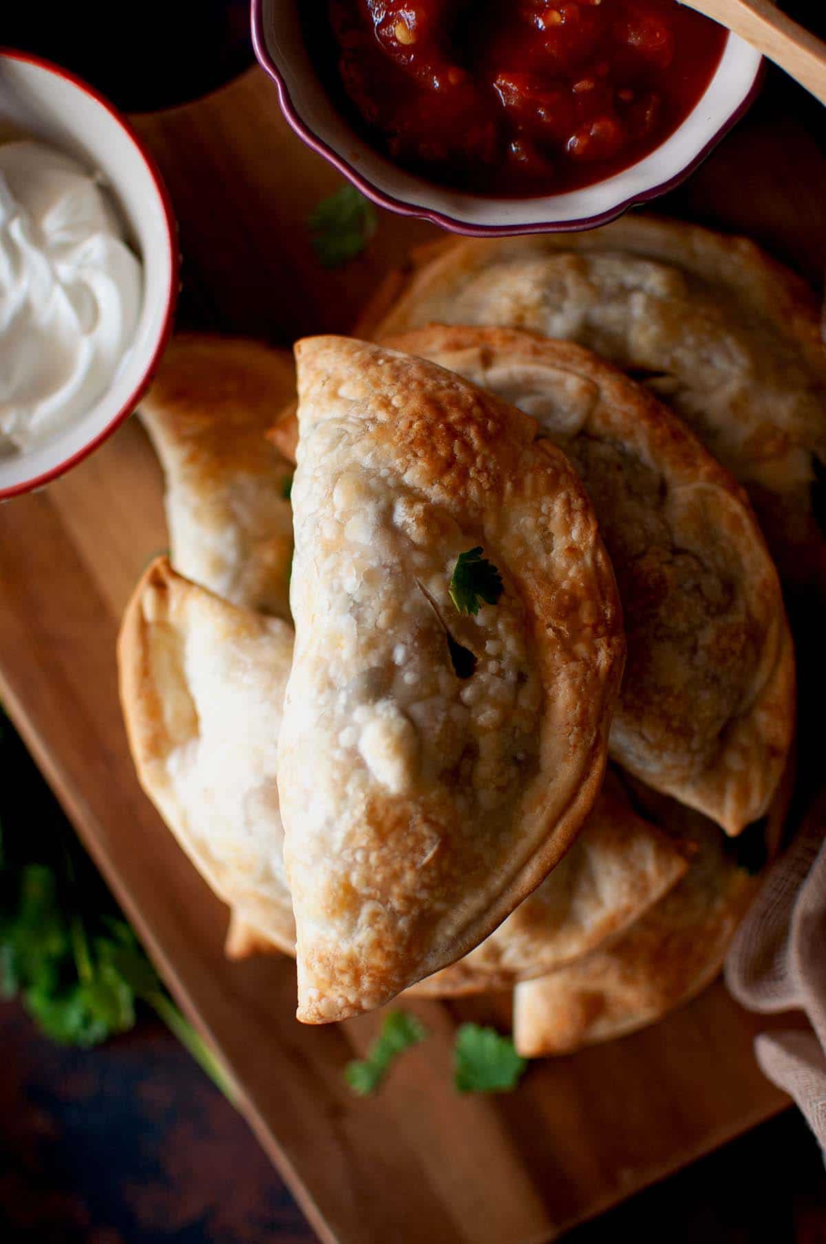 Chopping board with a stack of baked emapanadas