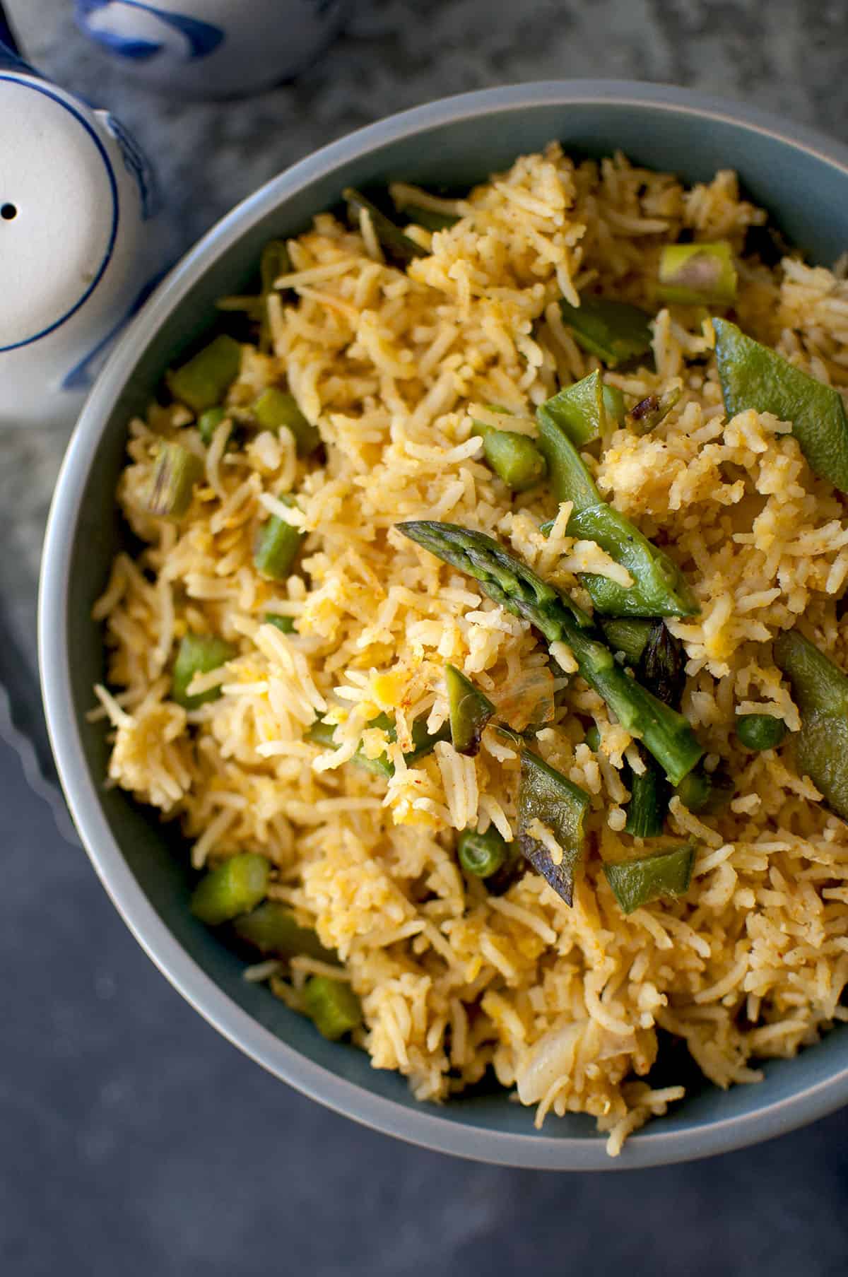 Blue bowl with vegetable khichdi topped with asparagus spear