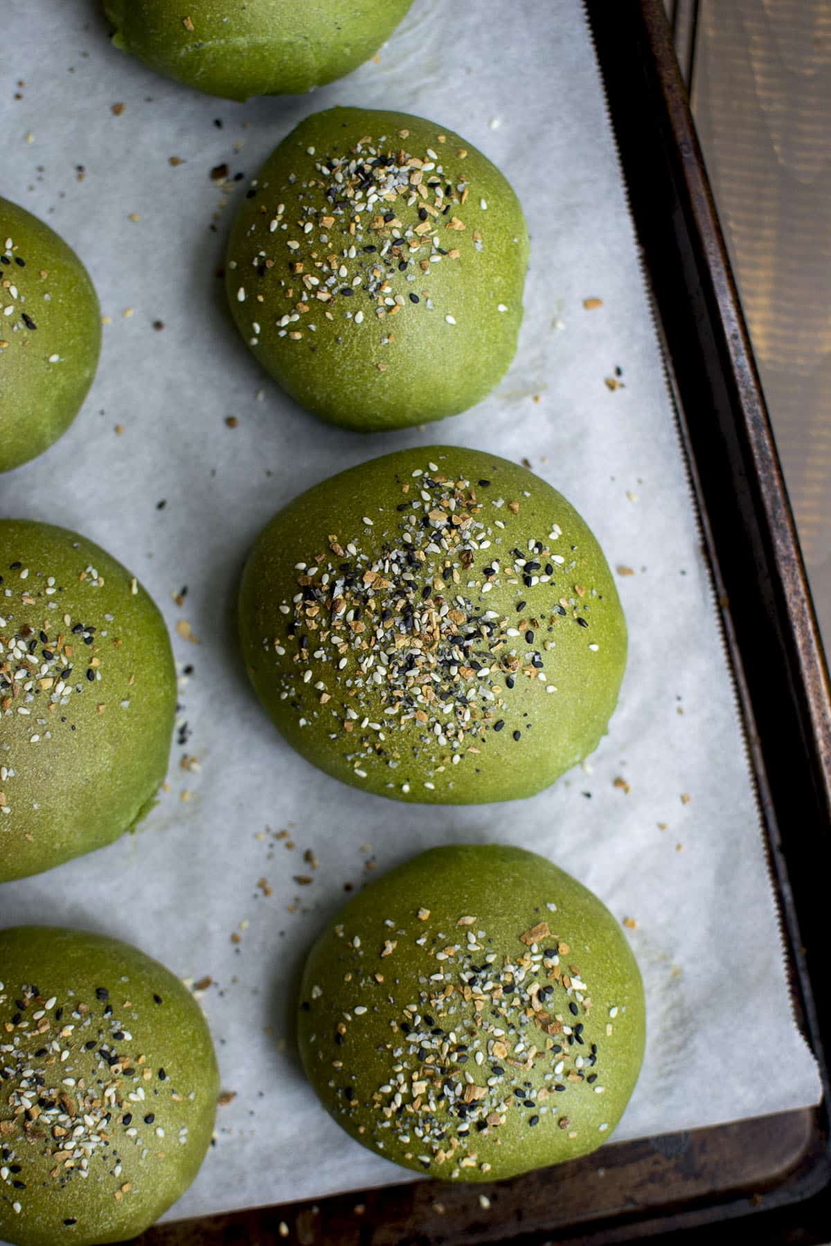 Parchment lined baking sheet with spinach flavored dinner rolls