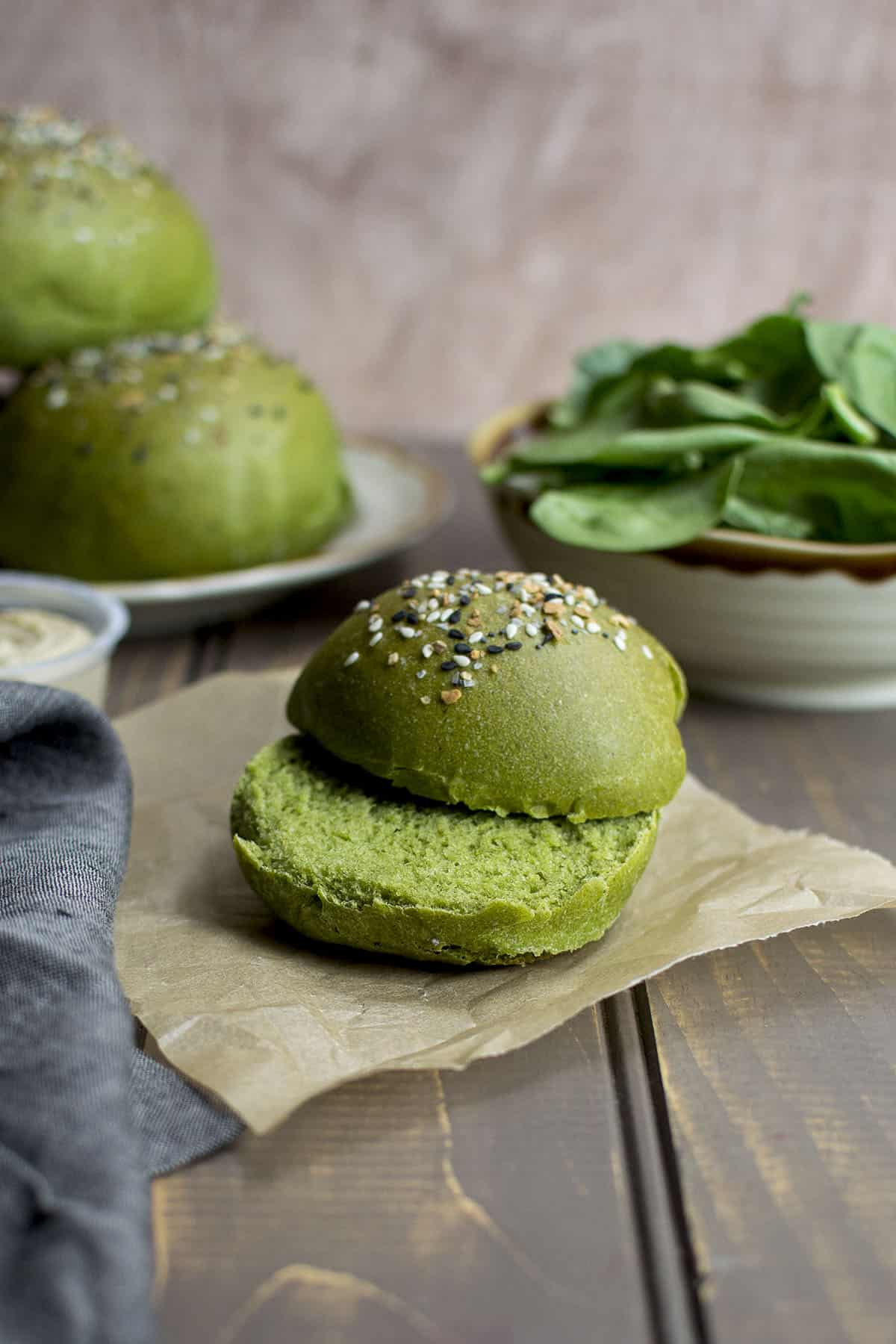 Slit spinach flavored sandwich roll on a parchment paper