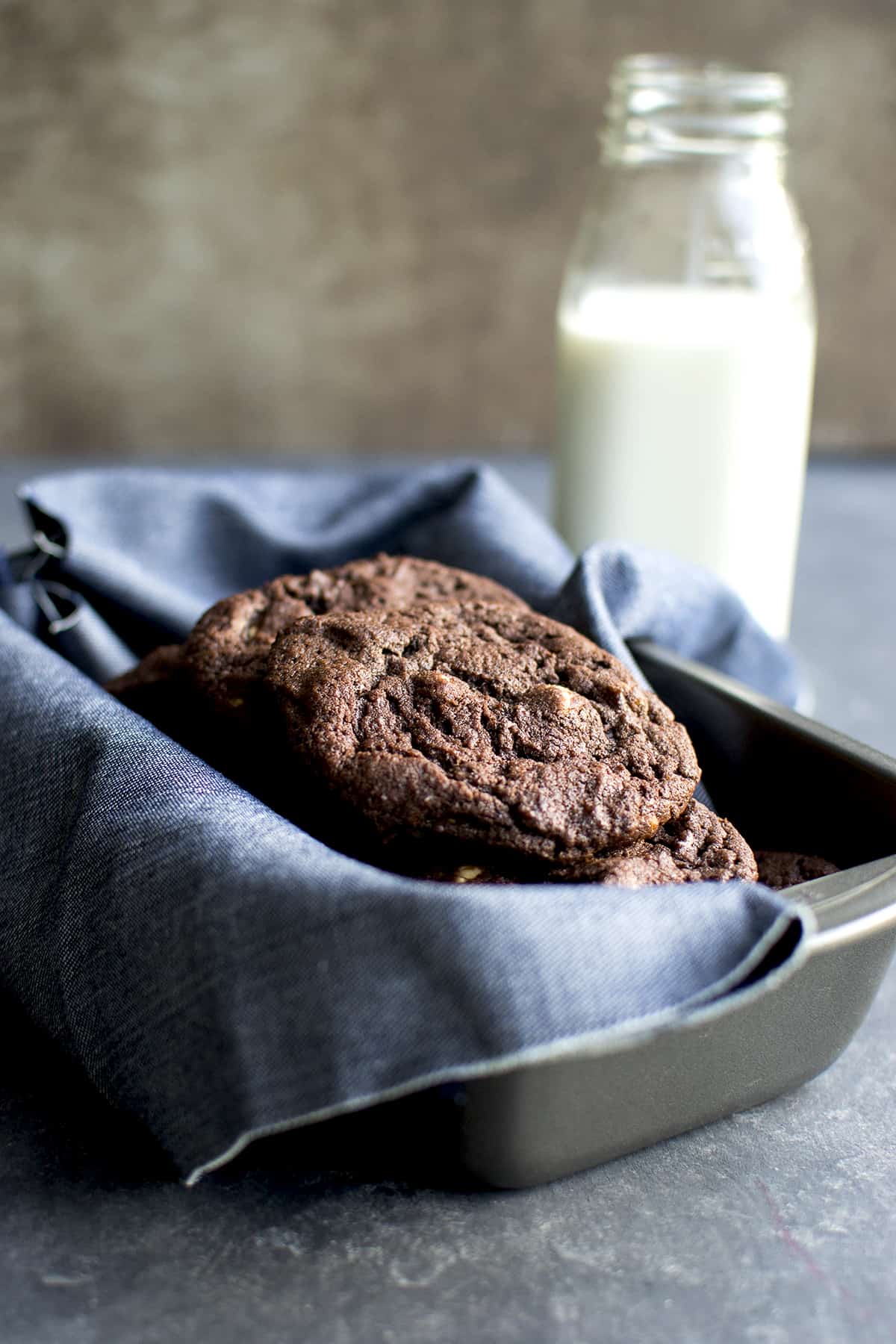 kitchen towel lined baking pan with chocolate drop cookies