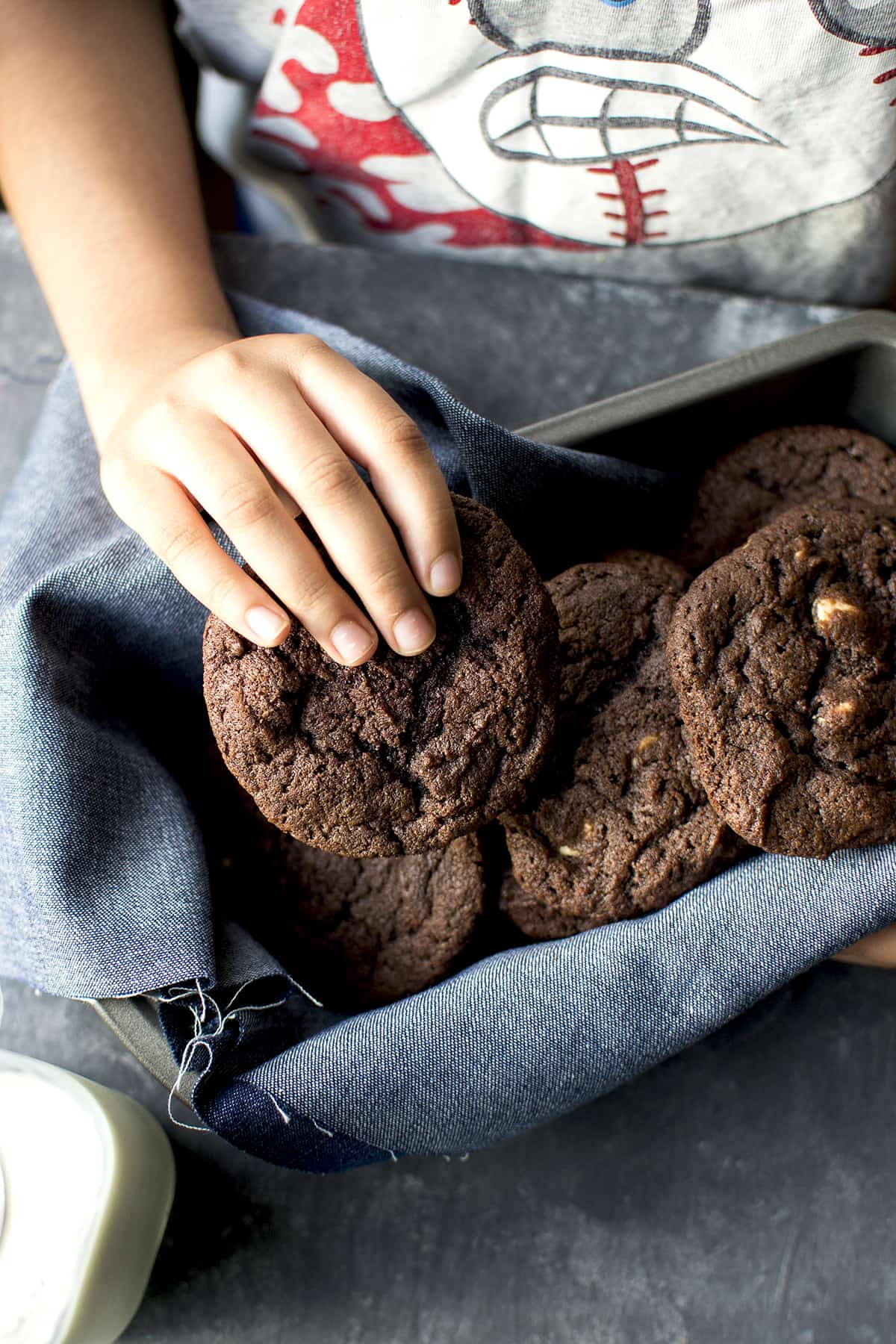 Kid holding a cookie from a stack of them