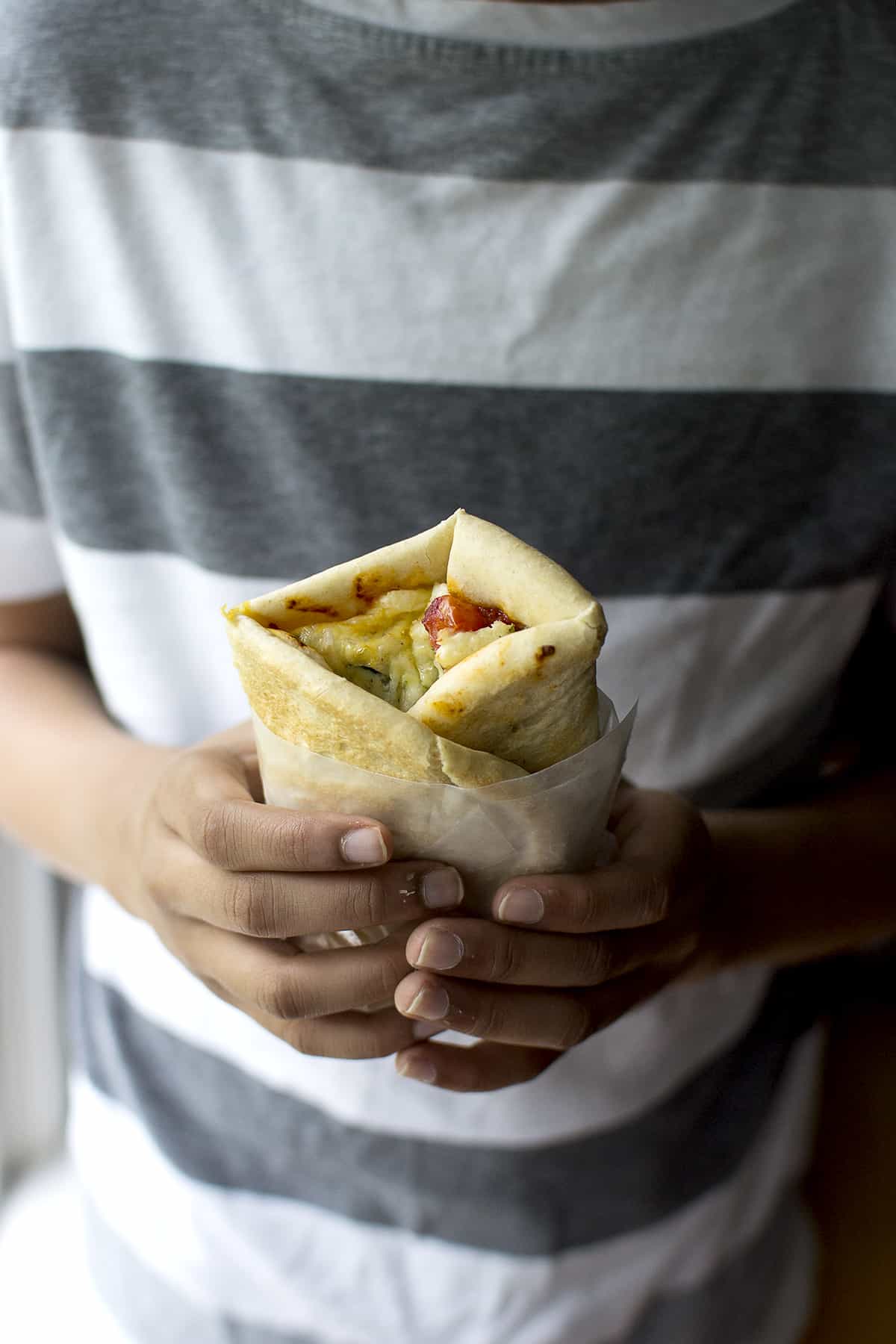 Person holding a folded Turkish Lahmacun pizza