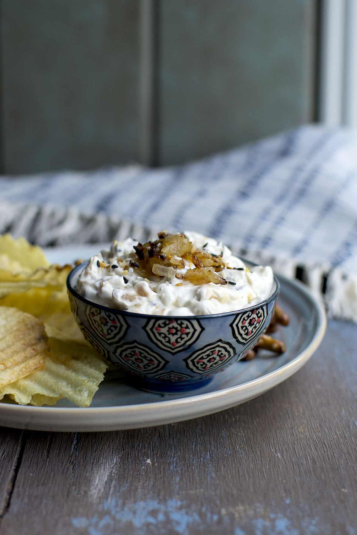 Blue bowl with creamy onion dip topped with caramelized onions