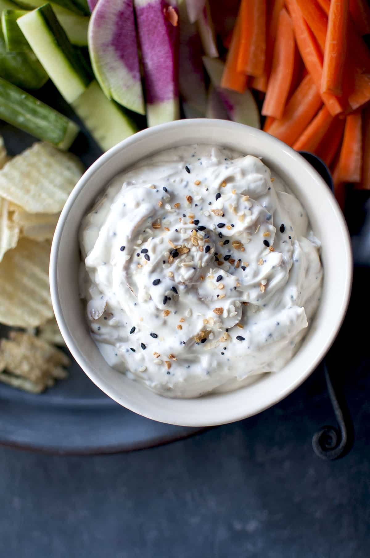 White bowl with creamy everything bagel tip and chips in the background