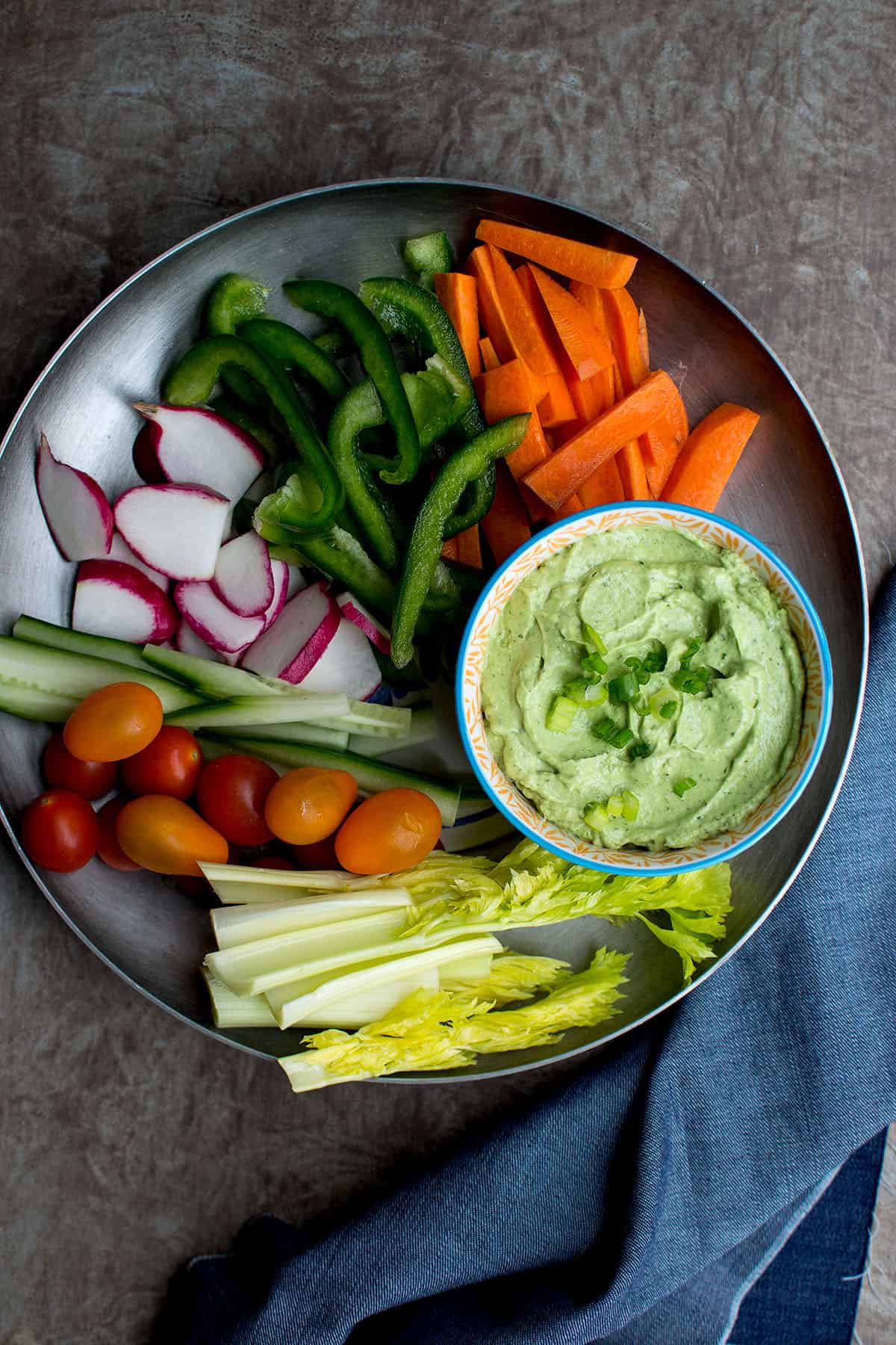 Pewter tray with a bowl of green goddess dip and chopped veggies.