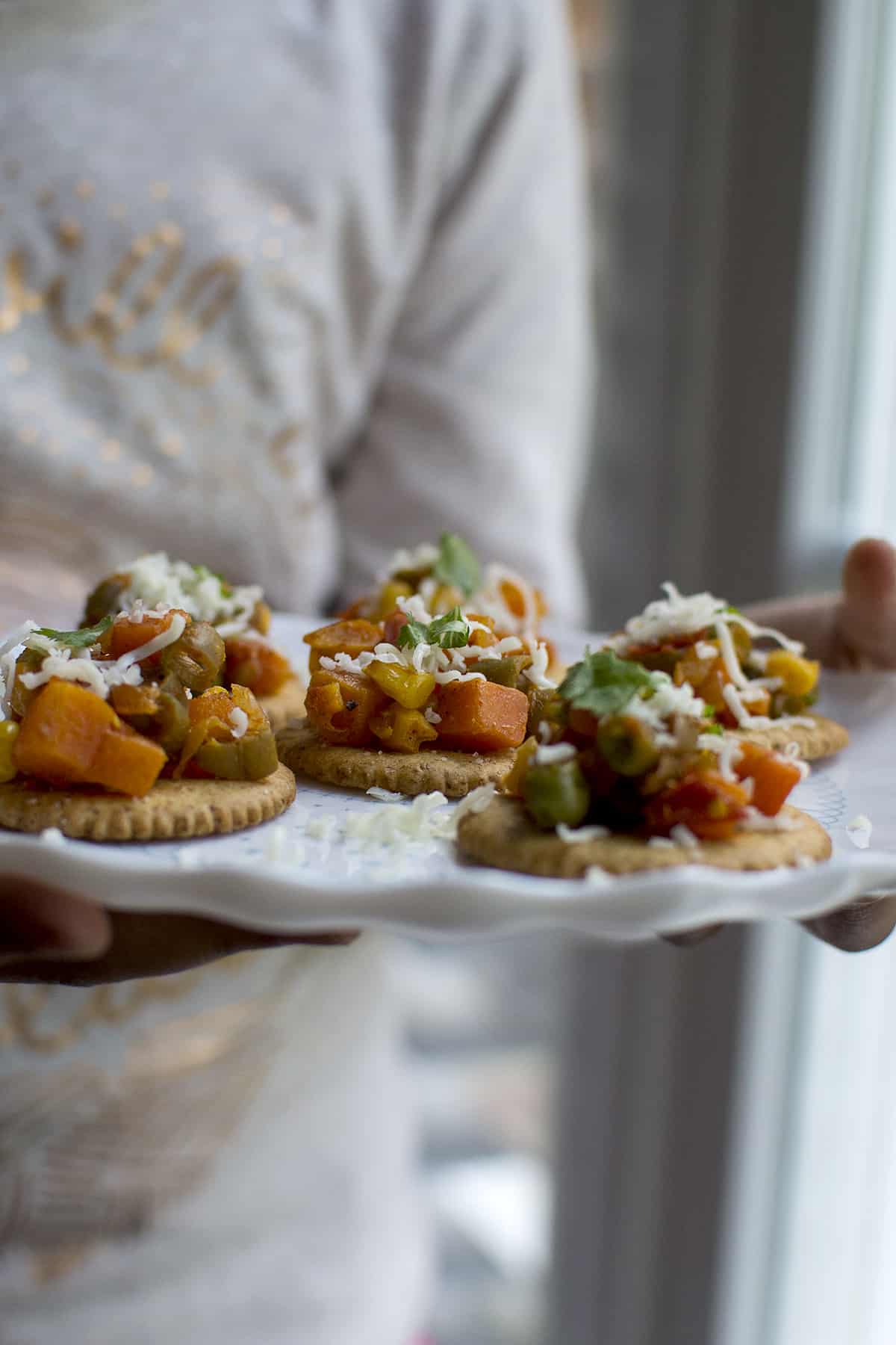 Person holding a white plate with Indian veg starter