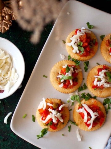 White plate with ritz crackers topped vegetable dip