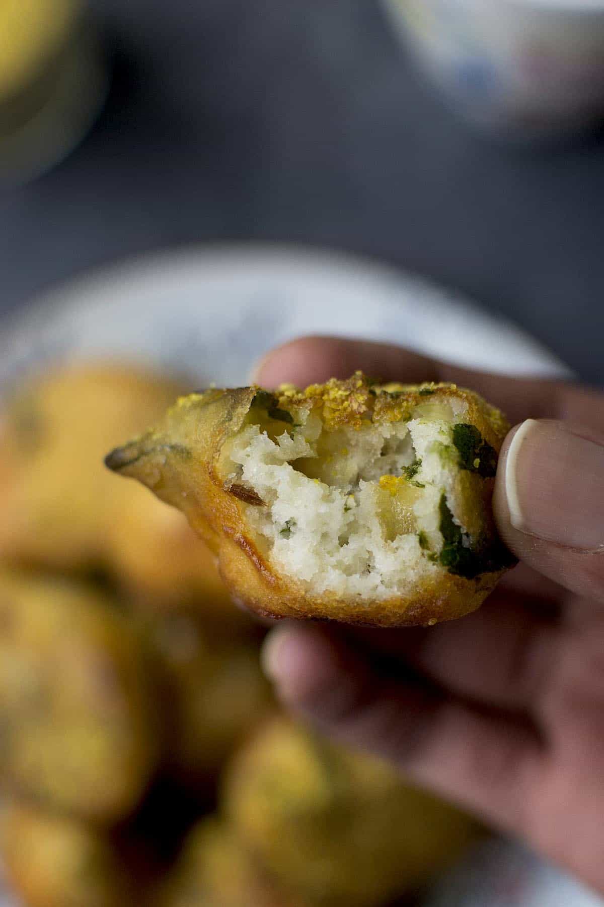 Hand holding a halved spinach fritter