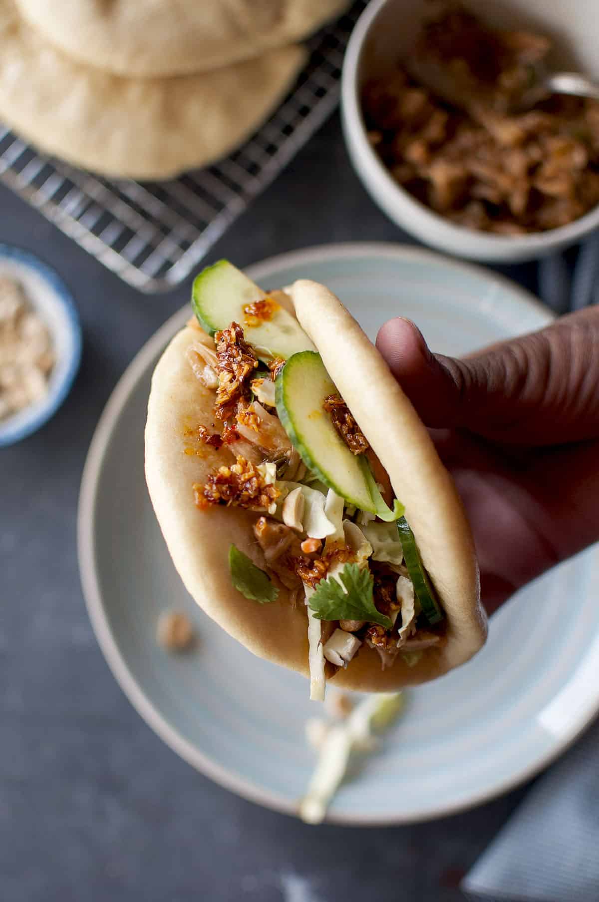 Hand holding steamed bun filled with jackfruit and veggies