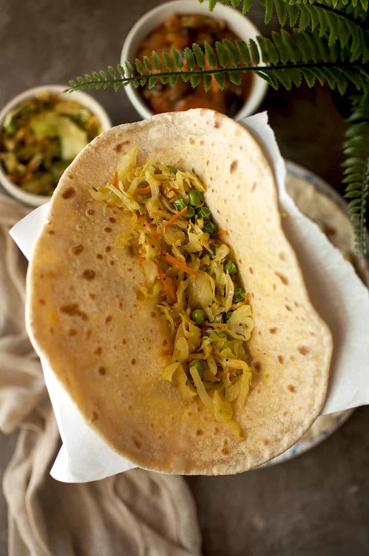 Hand holding dholl puri topped with curry