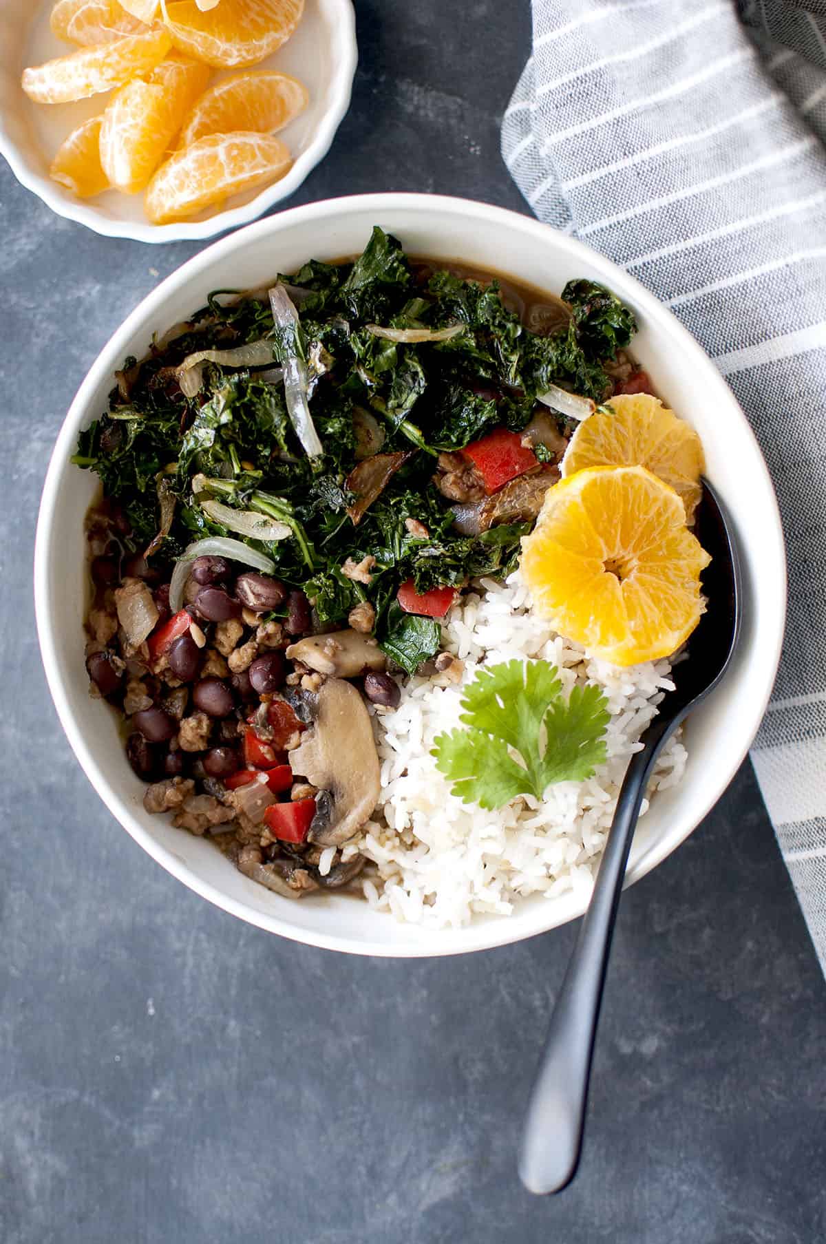 White bowl with Vegan Feijoada served with white rice and orange segments