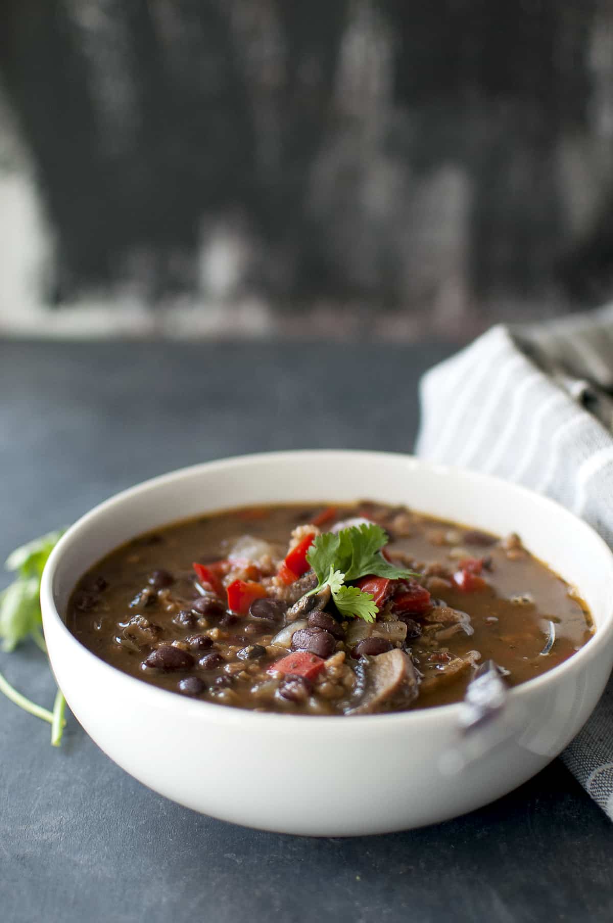 White bowl with Vegan Feijoada topped with cilantro and a spoon