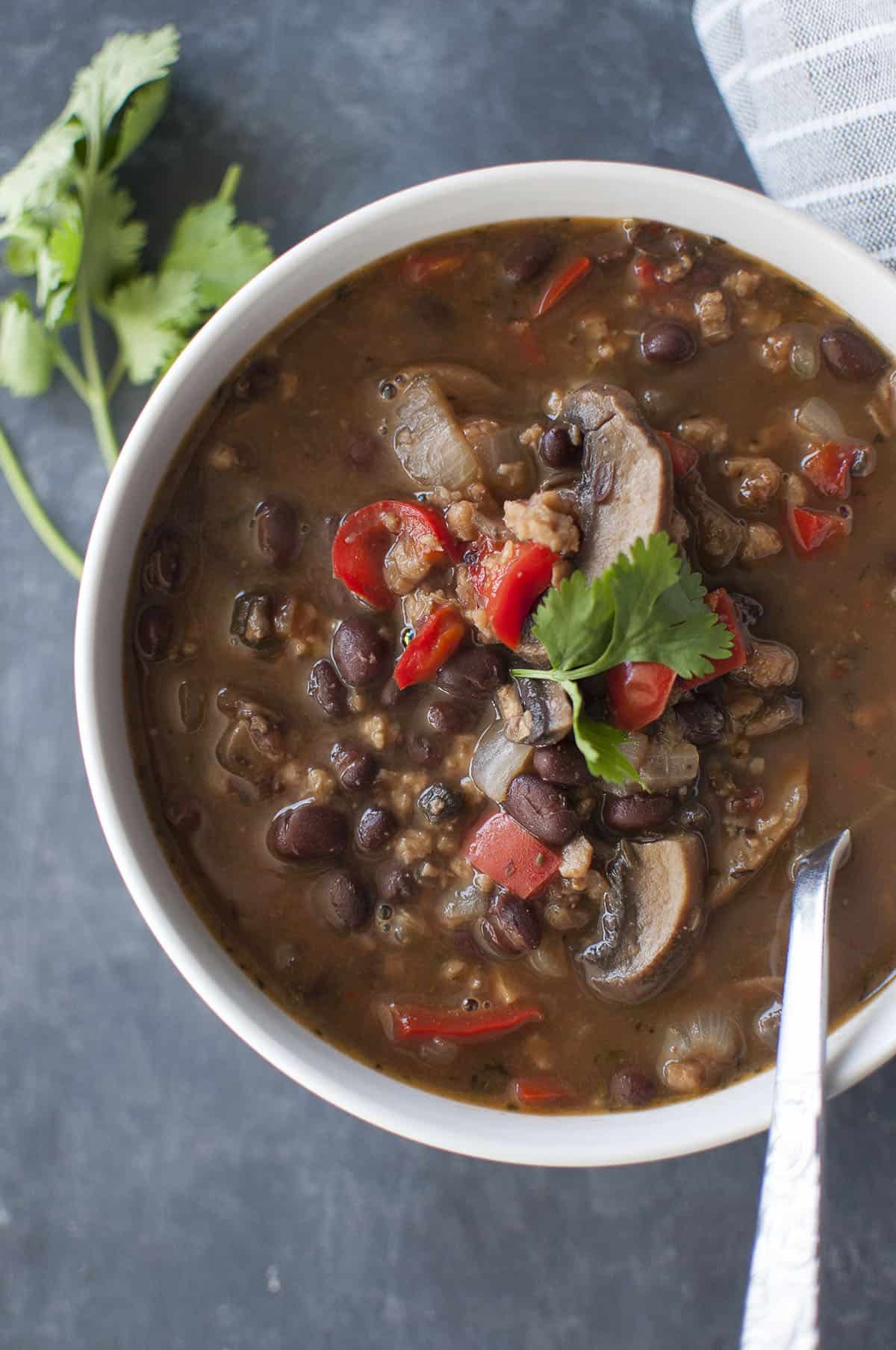 White bowl with chunky black bean stew topped with cilantro