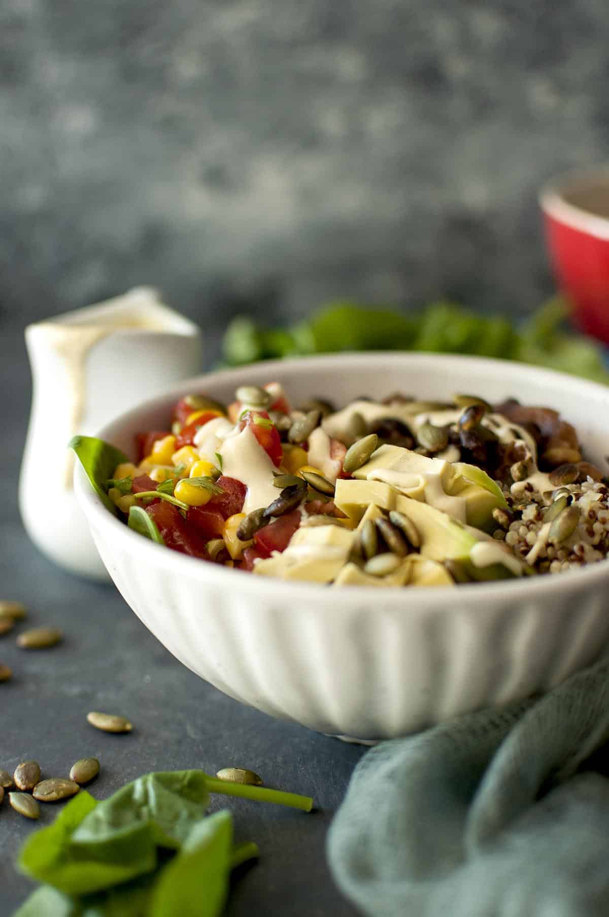 White bowl with quinoa, beans and cashew sauce