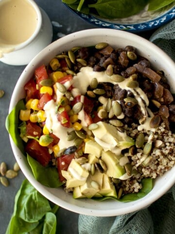 Top view of a white bowl with quinoa, beans, salsa and sauce