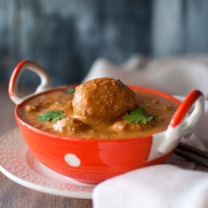 Orange serving bowl with spicy potato curry.