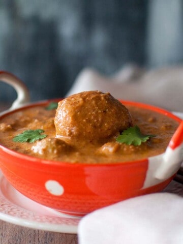 Orange serving bowl with spicy potato curry.