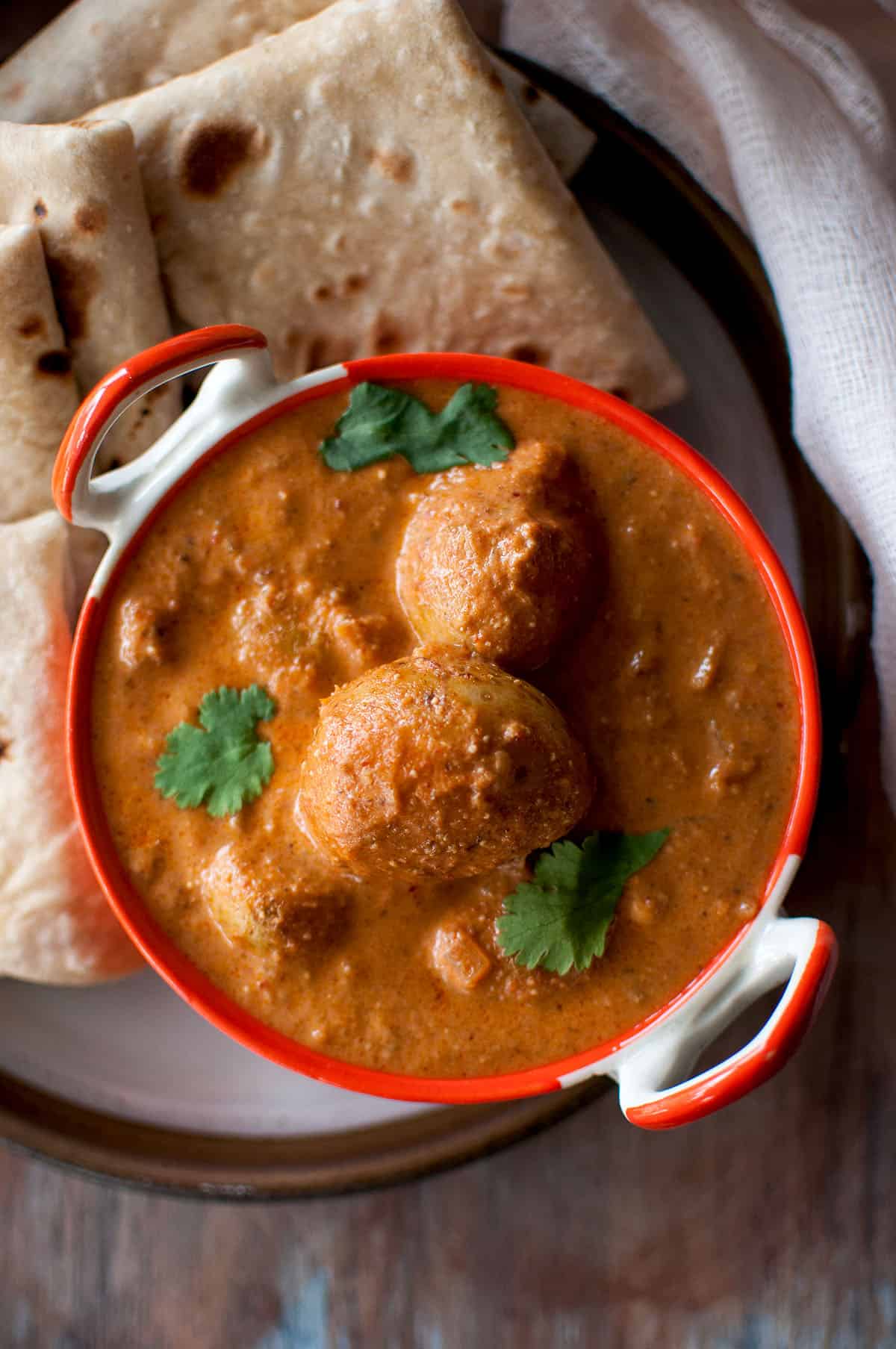 Top view of orange bowl with Lahori dum aloo.