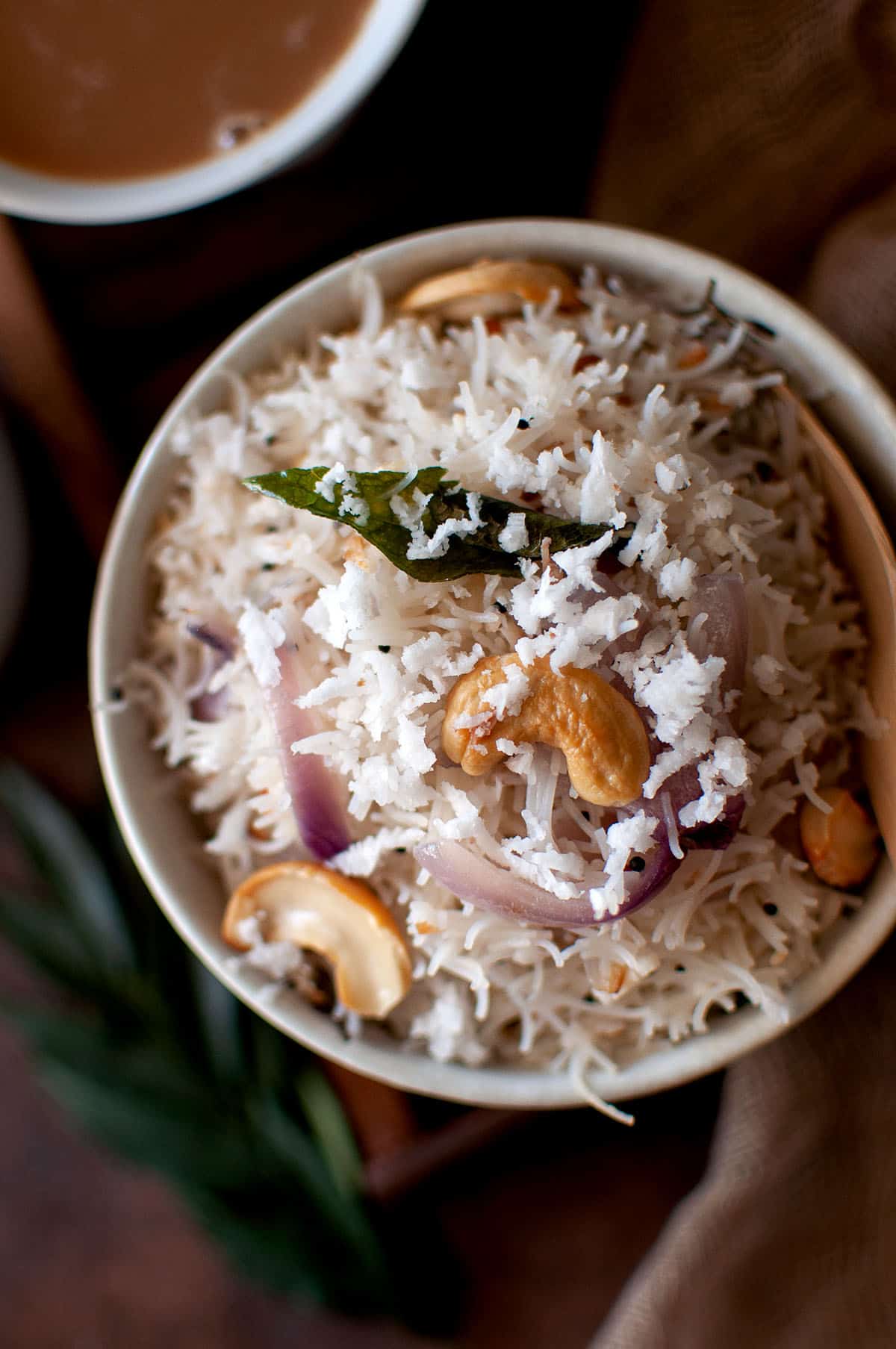 Top view of a white bowl with rice vermicelli topped with coconut.