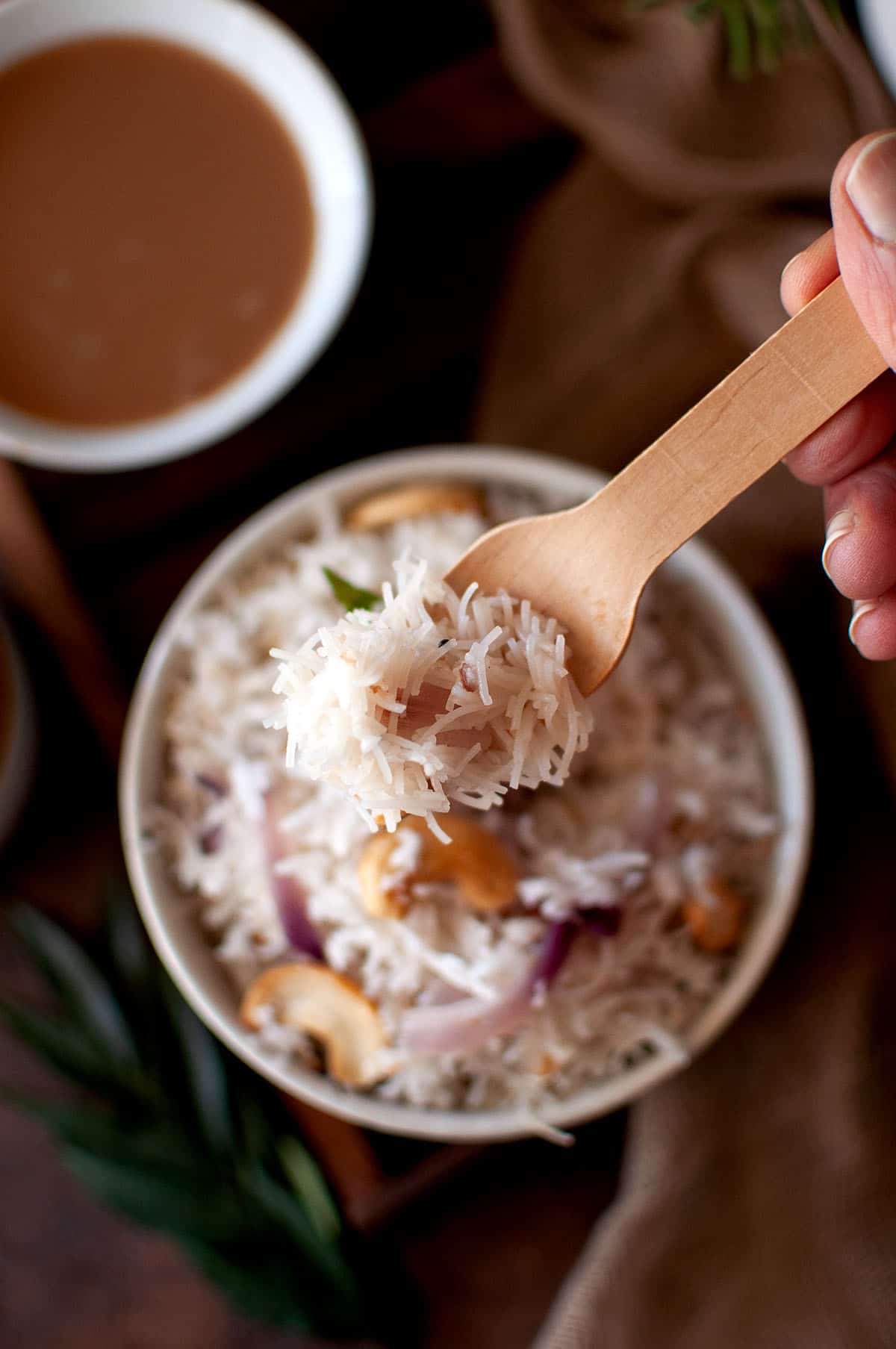 Hand holding a wooden fork with vermicelli.
