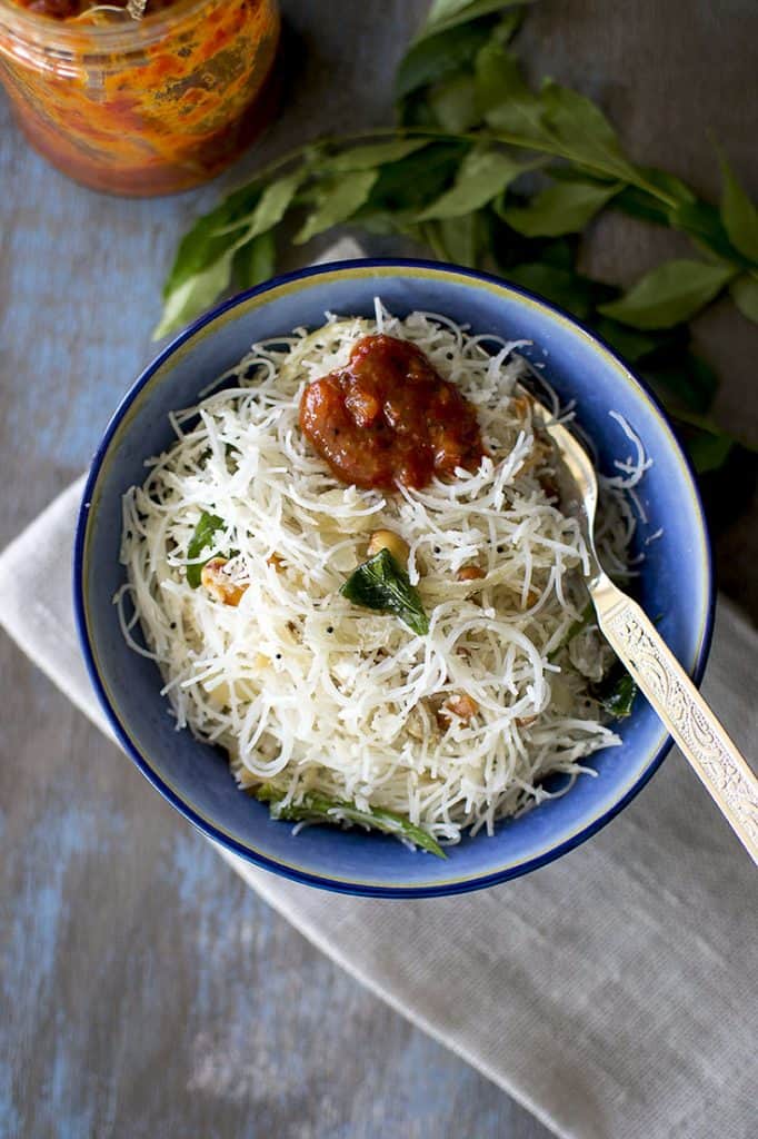 Bowl of rice noodles with pickle on top.