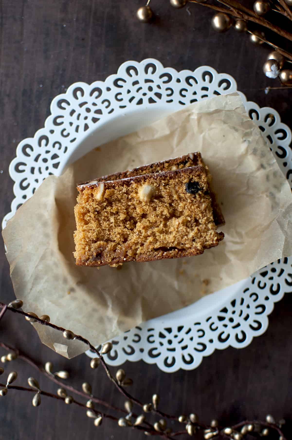 White plate with a parchment and a slice of fruit cake