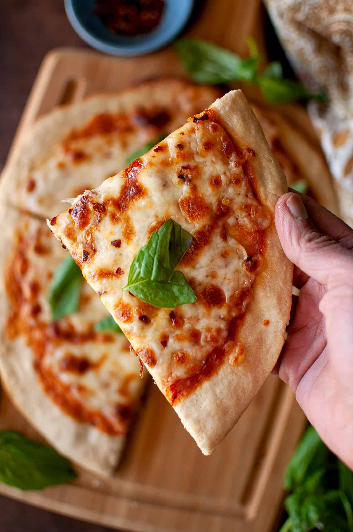 Hand holding a slice of cheese pizza.