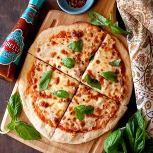 Wooden board with cheese topped flatbread.