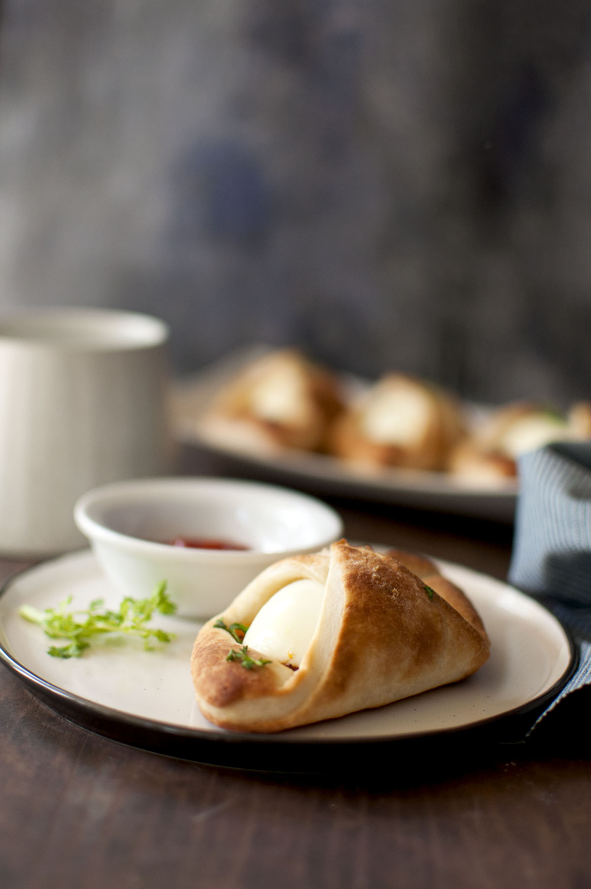 Black plate with egg puff and small bowl with ketchup