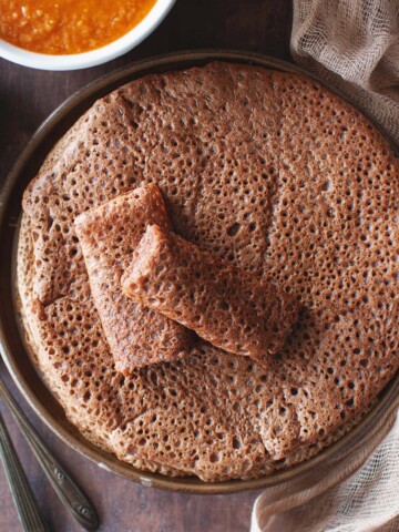 Brown plate with a stack of Ethiopian flatbread.