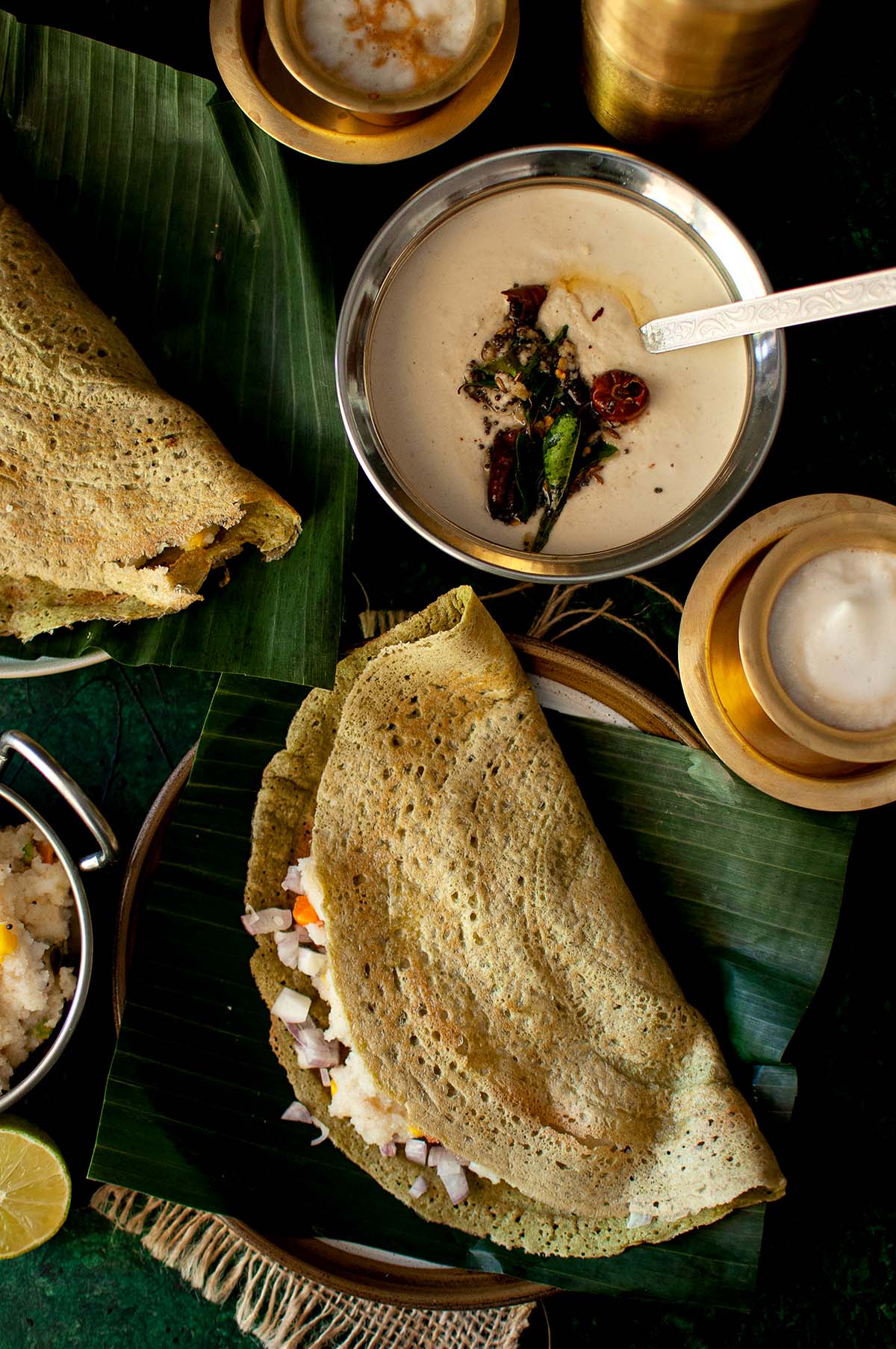 Plates of green gram dosa and bowls with chutneys.